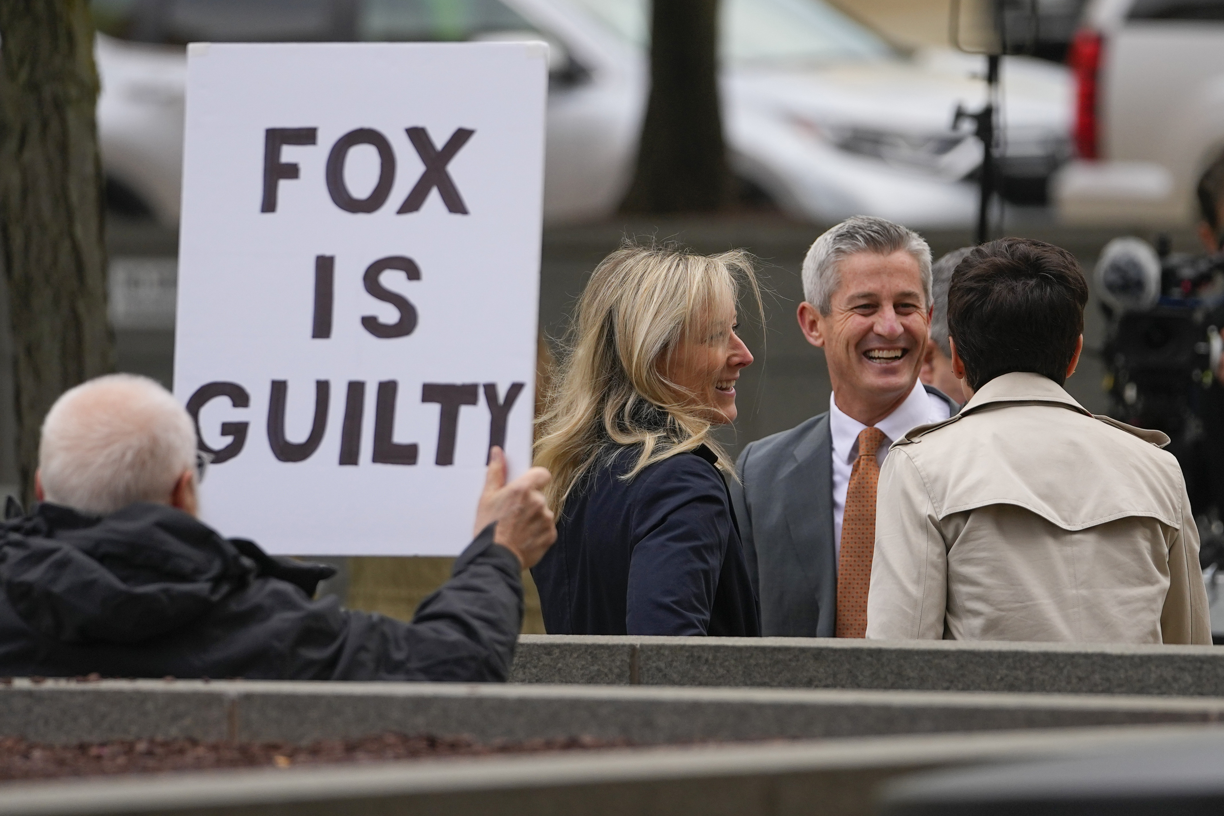 A protester holds a sign near representatives of Fox News in Wilmington, Delaware