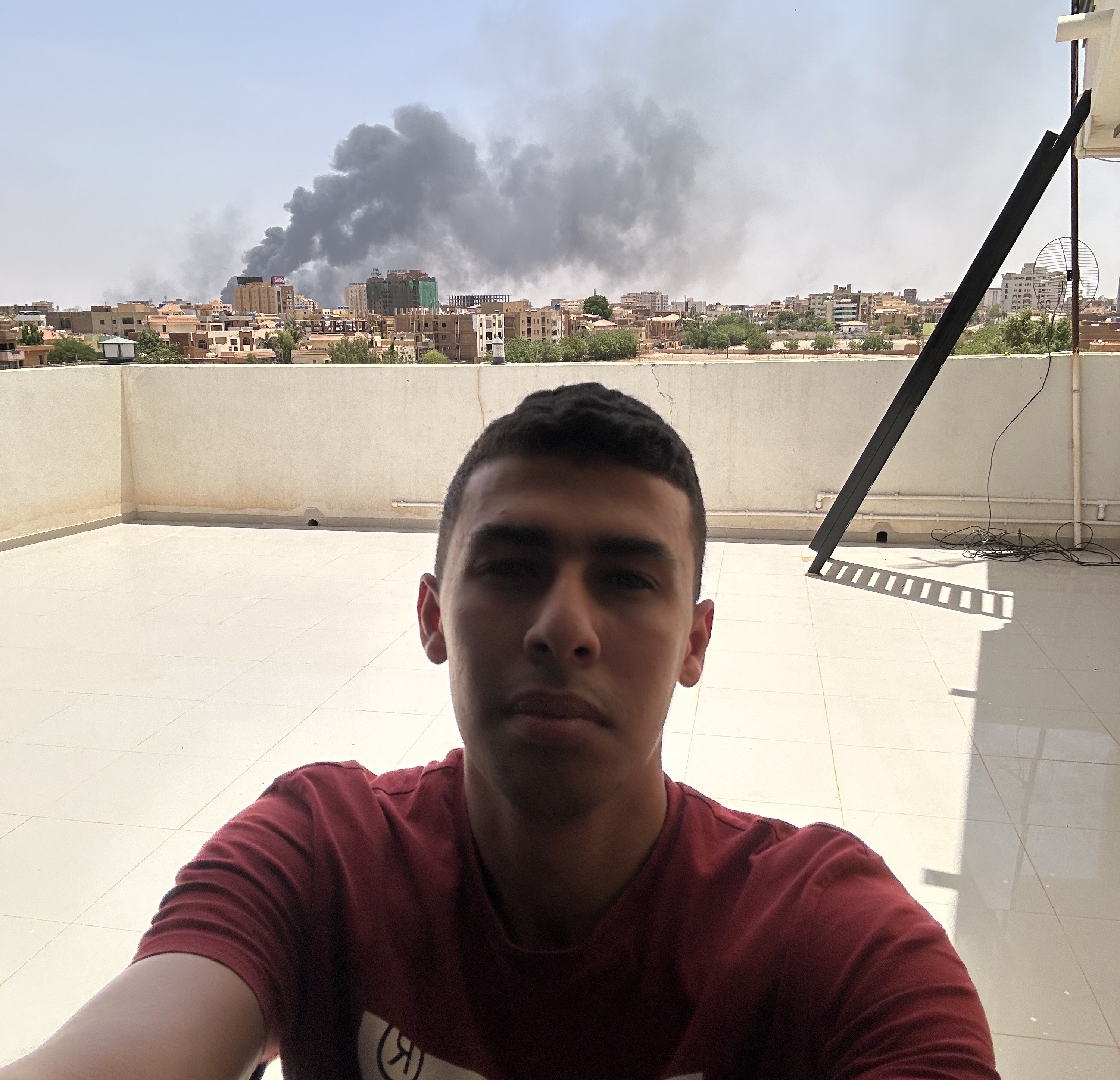 Plumes of smoke rise in the distance as Ahmed El-Badawy follows developments from the rooftop where he is staying during the fighting