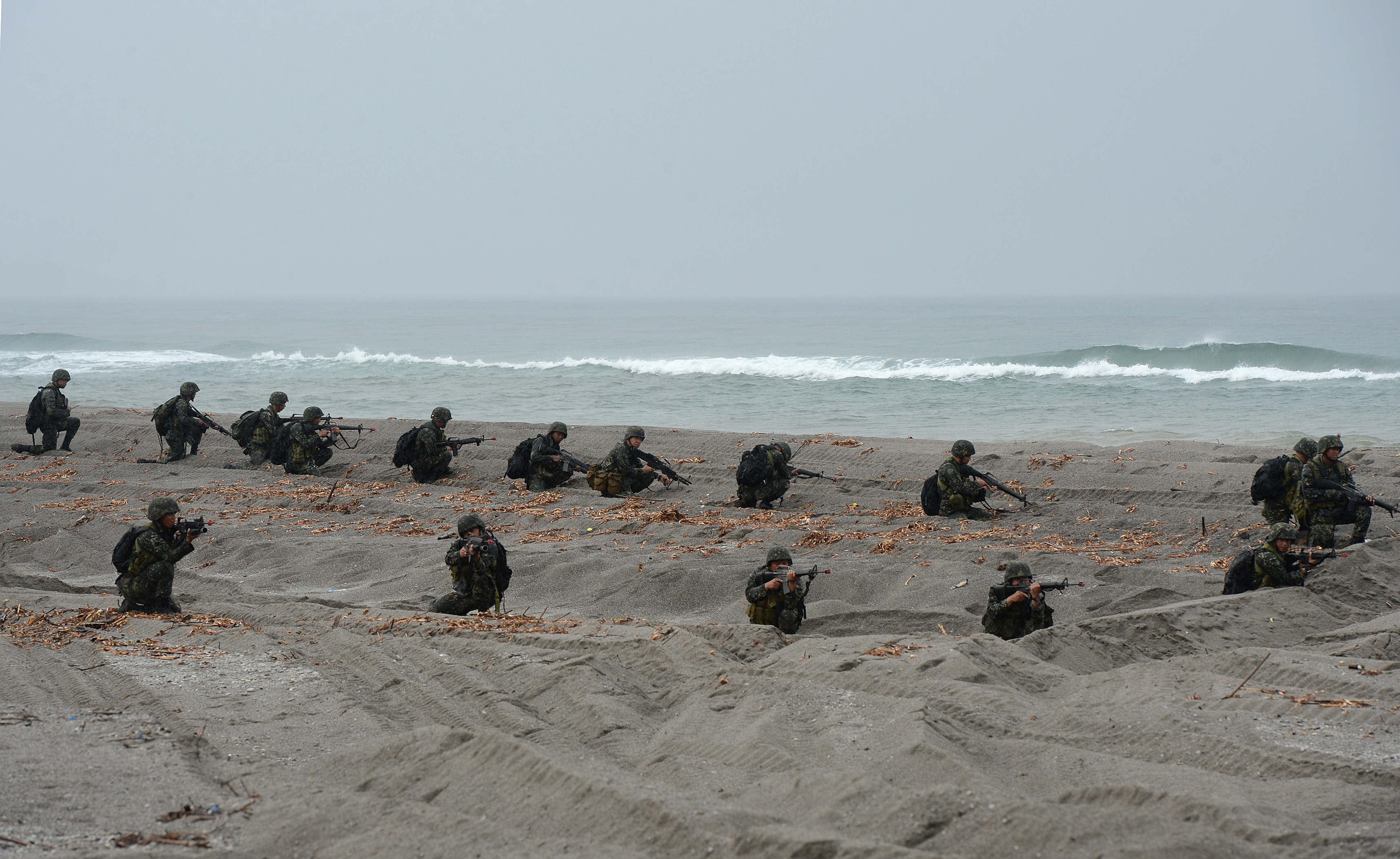Philippine Marines take their position during a mock beach assault along with their US counterparts as part of Cooperation Afloat Readiness and Training (CARAT 2014) along the beach at a Philippine naval training base facing the South China Sea in San Antonio, Zambales province, north of Manila on June 30, 2014. Naval forces from the US and Philippines engaged in an amphibious landing on June 30 on Luzon island amid a tense territorial row with China. AFP PHOTO / TED ALJIBE (Photo by TED ALJIBE / AFP)