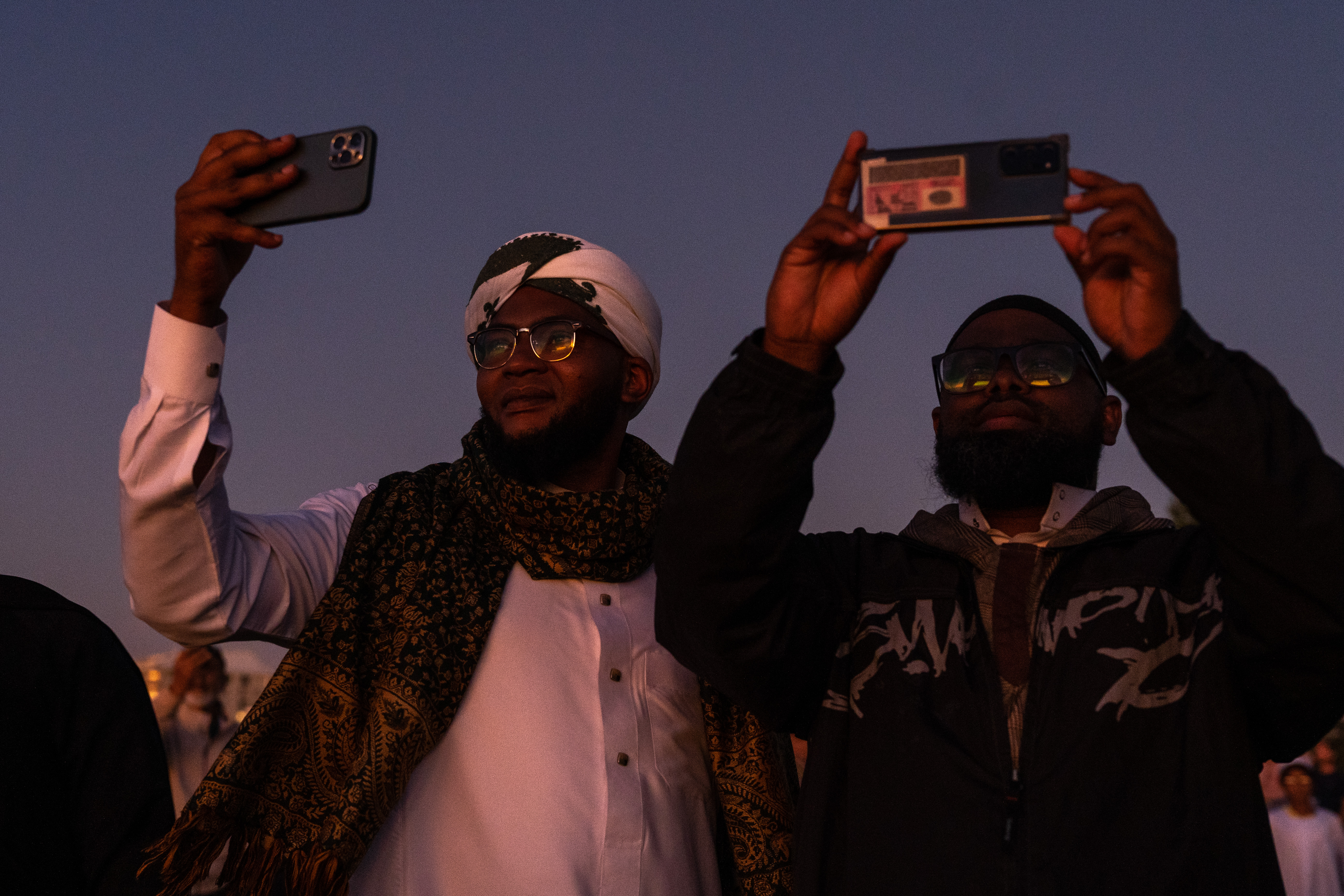 Two men take photos of the sky as they wait to hear whether the moon has been sighted