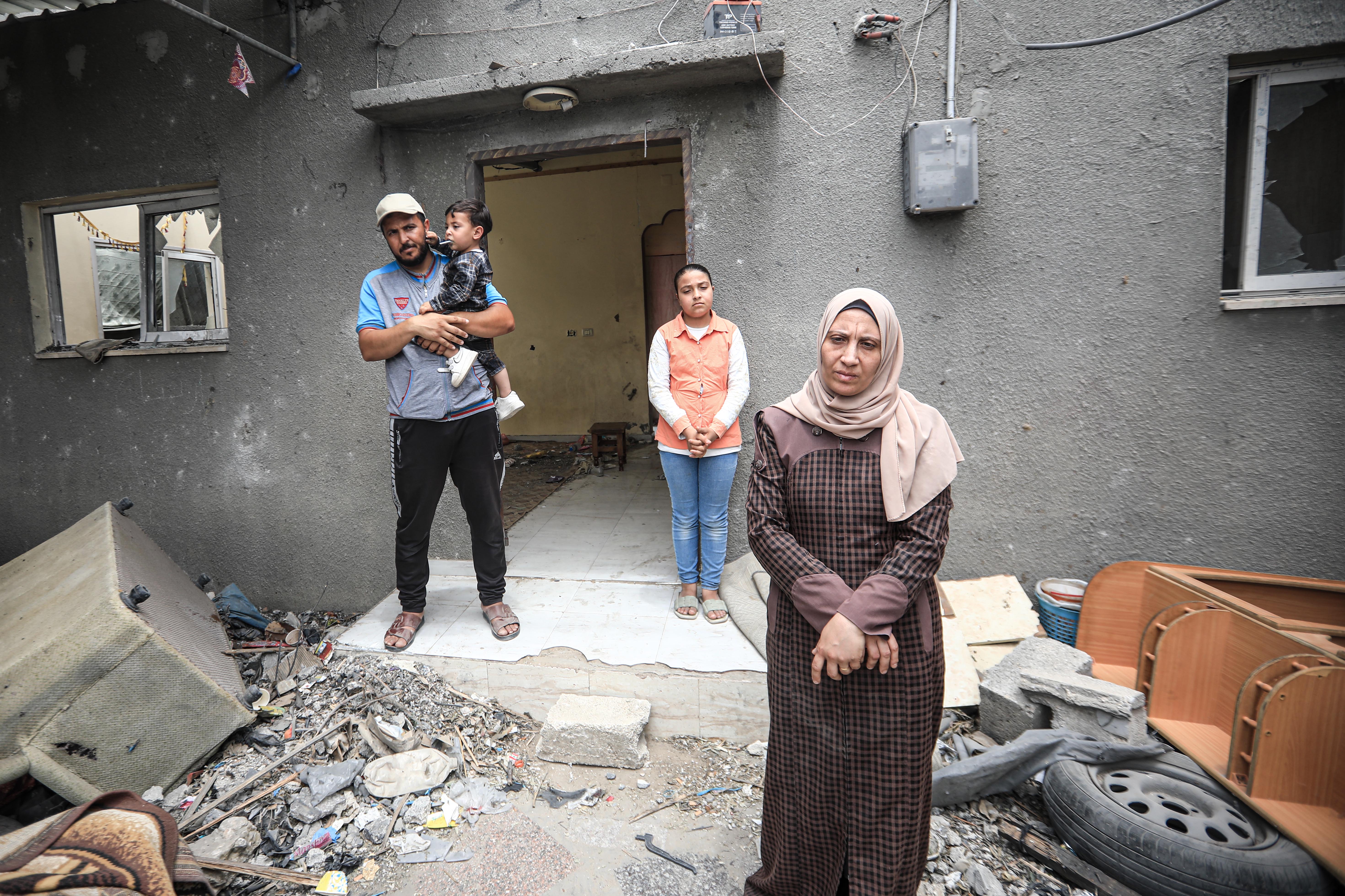 Aisha, her husband and their children in front of their badly damaged home in Deir al-Balah central of the Gaza Strip