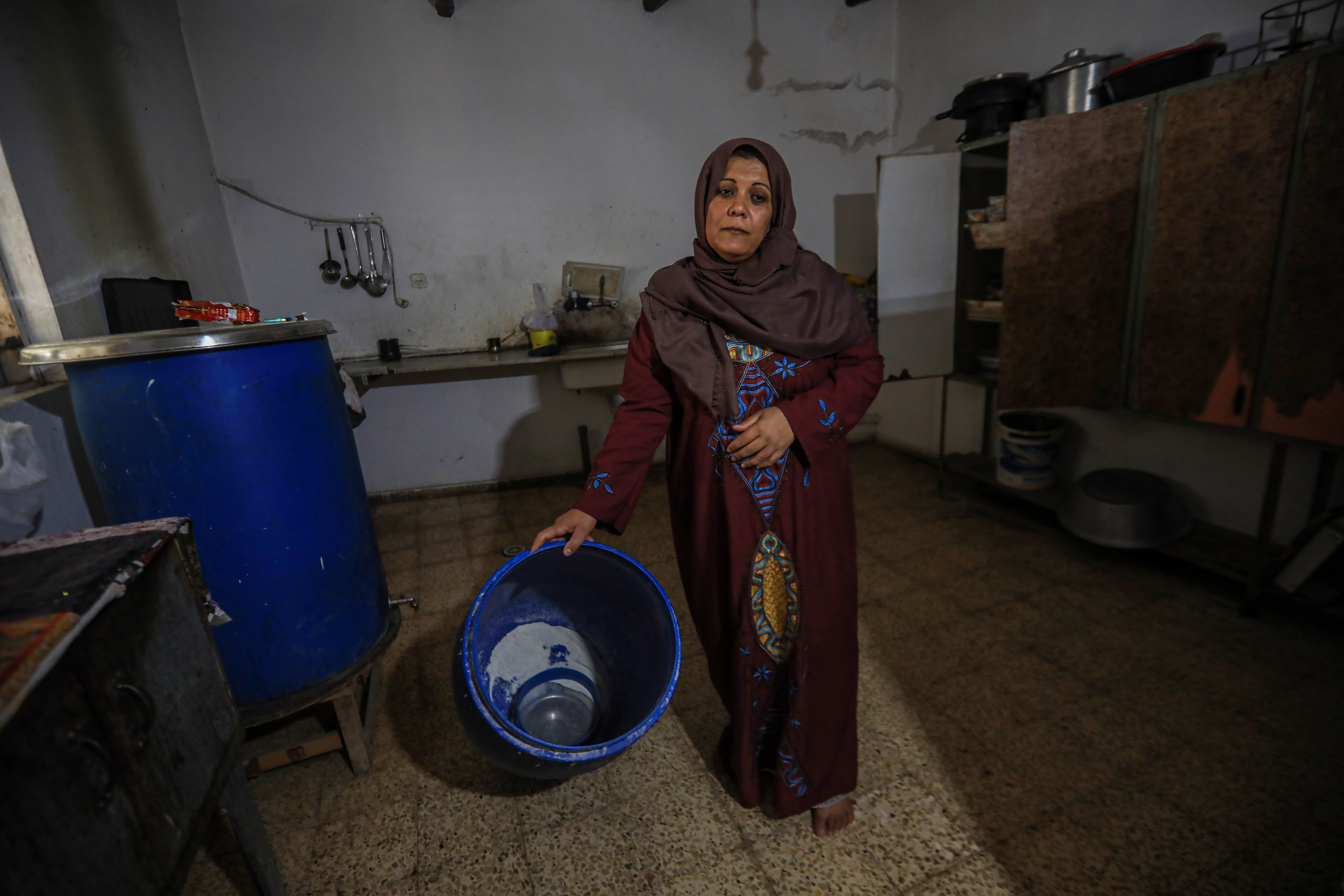 Samah al-Qanou, who lives in dire conditions north of Gaza, shows an almost empty barrel of flour