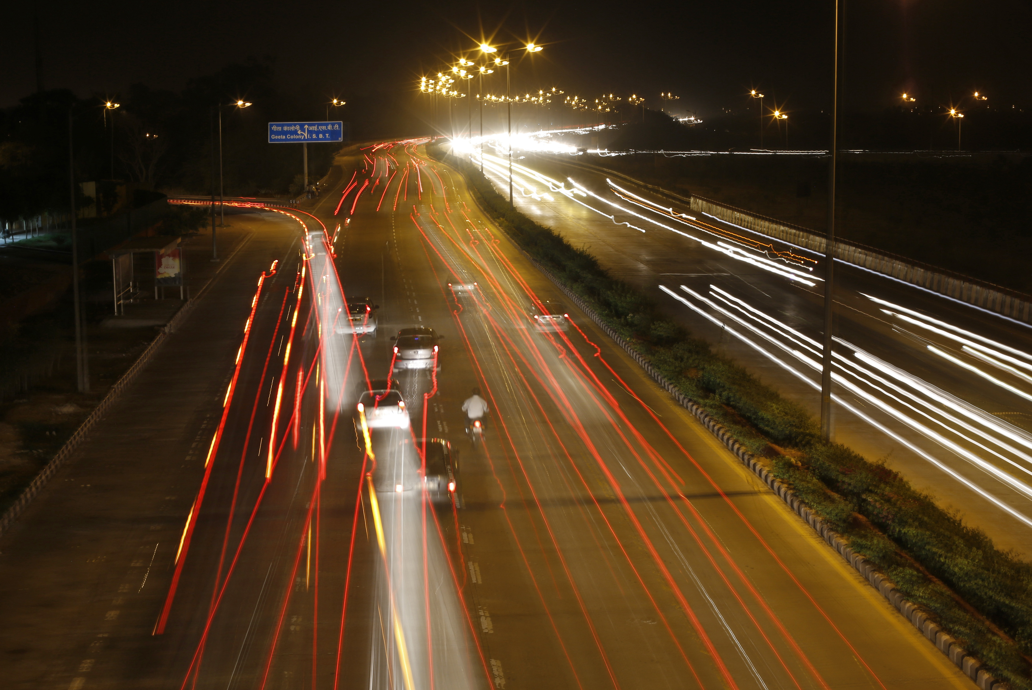Cars drive on a road in Delhi at night