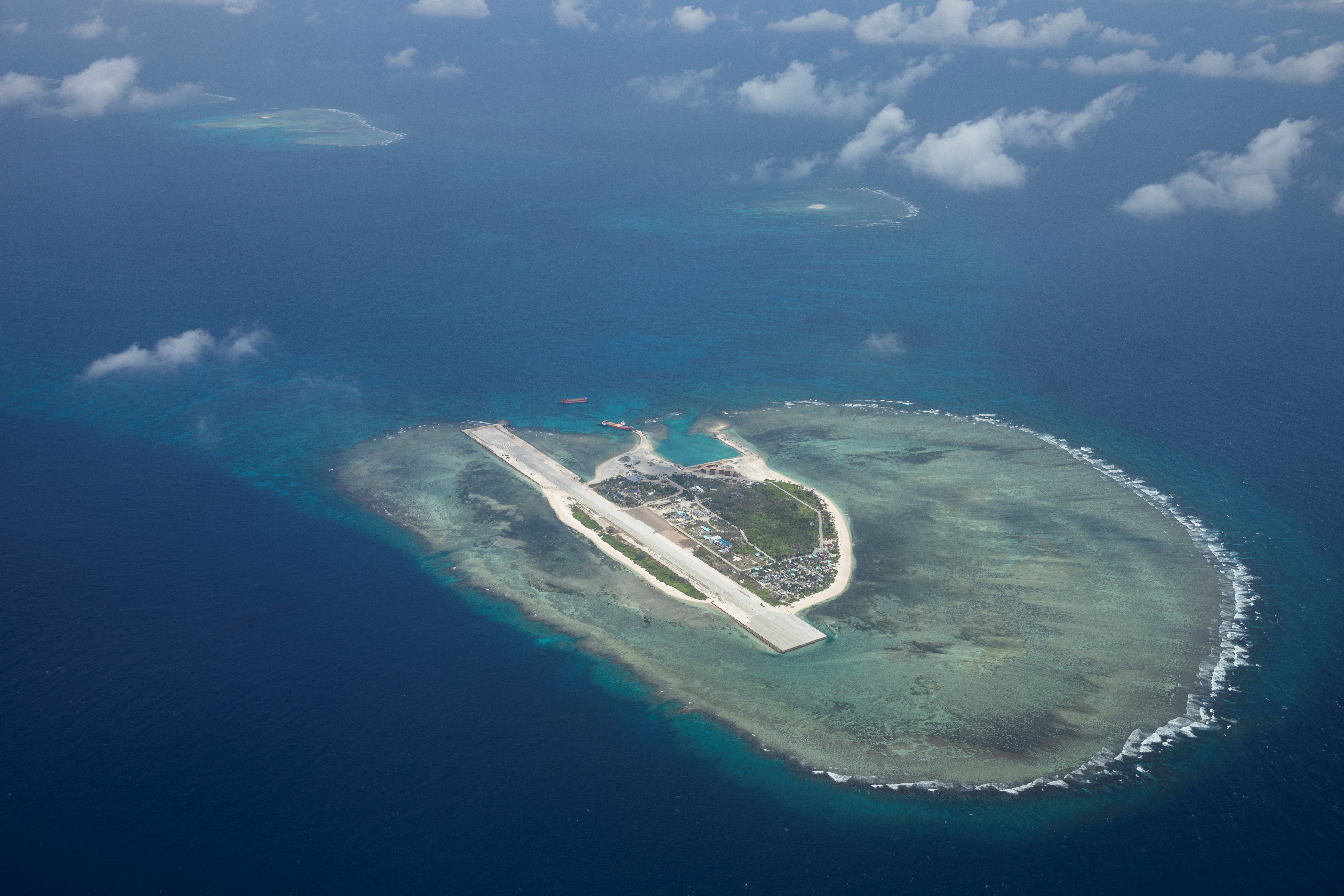 An island, seen from above, in the midst of a vast sea. A runway can be seen on the island.