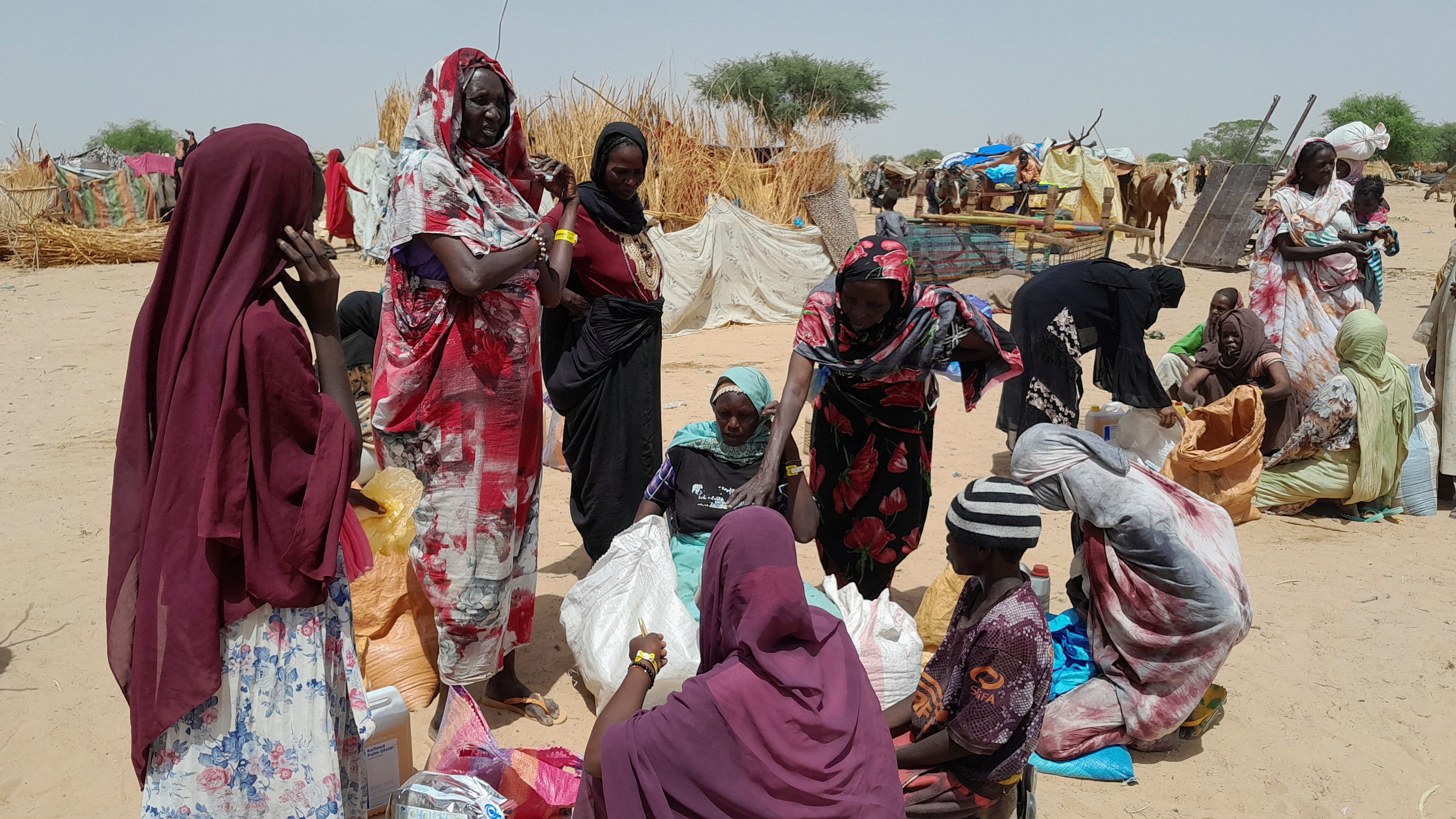 Sudanese refugees who have fled the violence in their country gather to receive food supplements from World Food Programme (WFP), near the border between Sudan and Chad.