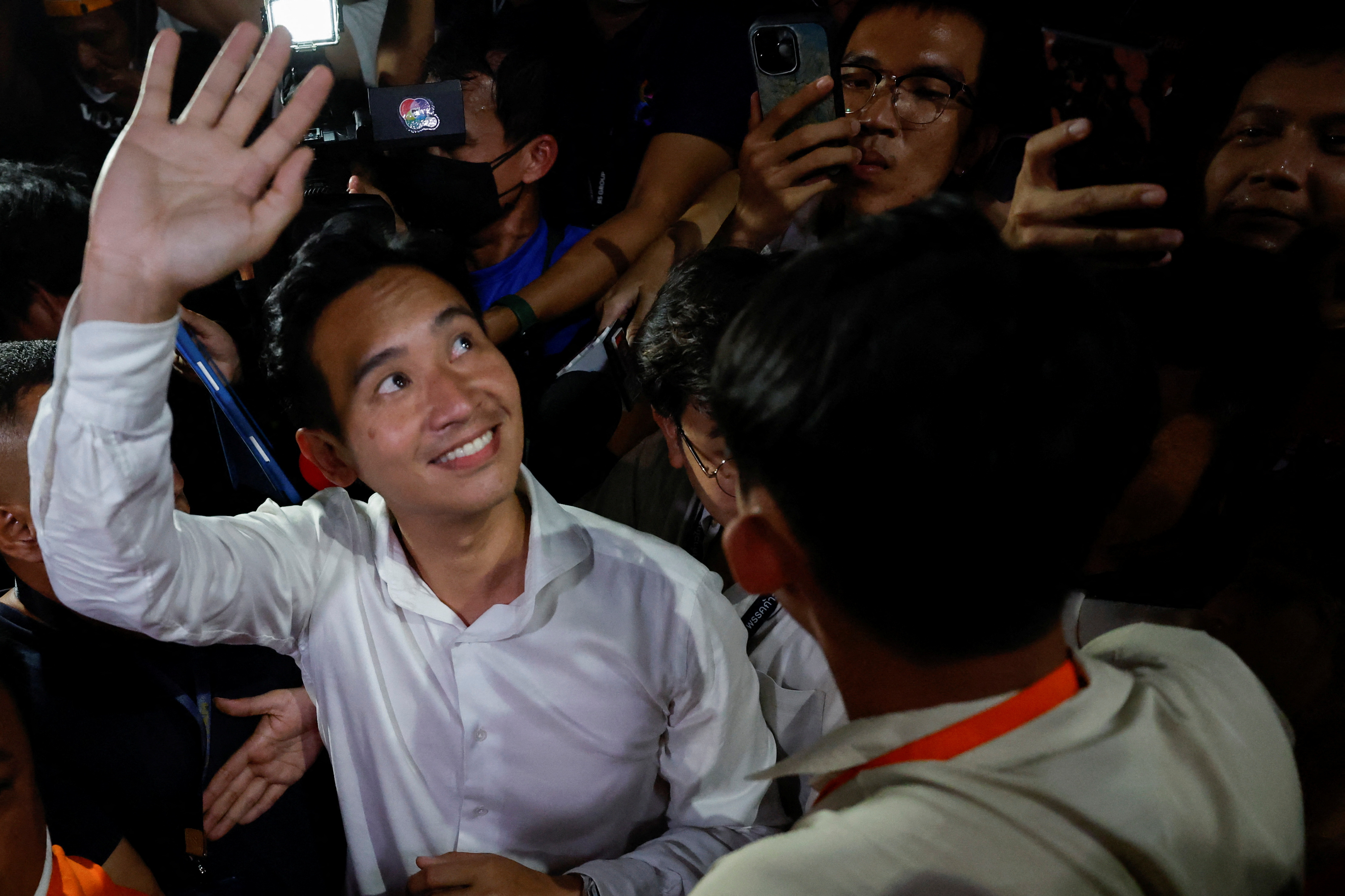 Move Forward Party leader and prime ministerial candidate, Pita Limjaroenrat, waves to the crowd. He is smiling and happy.