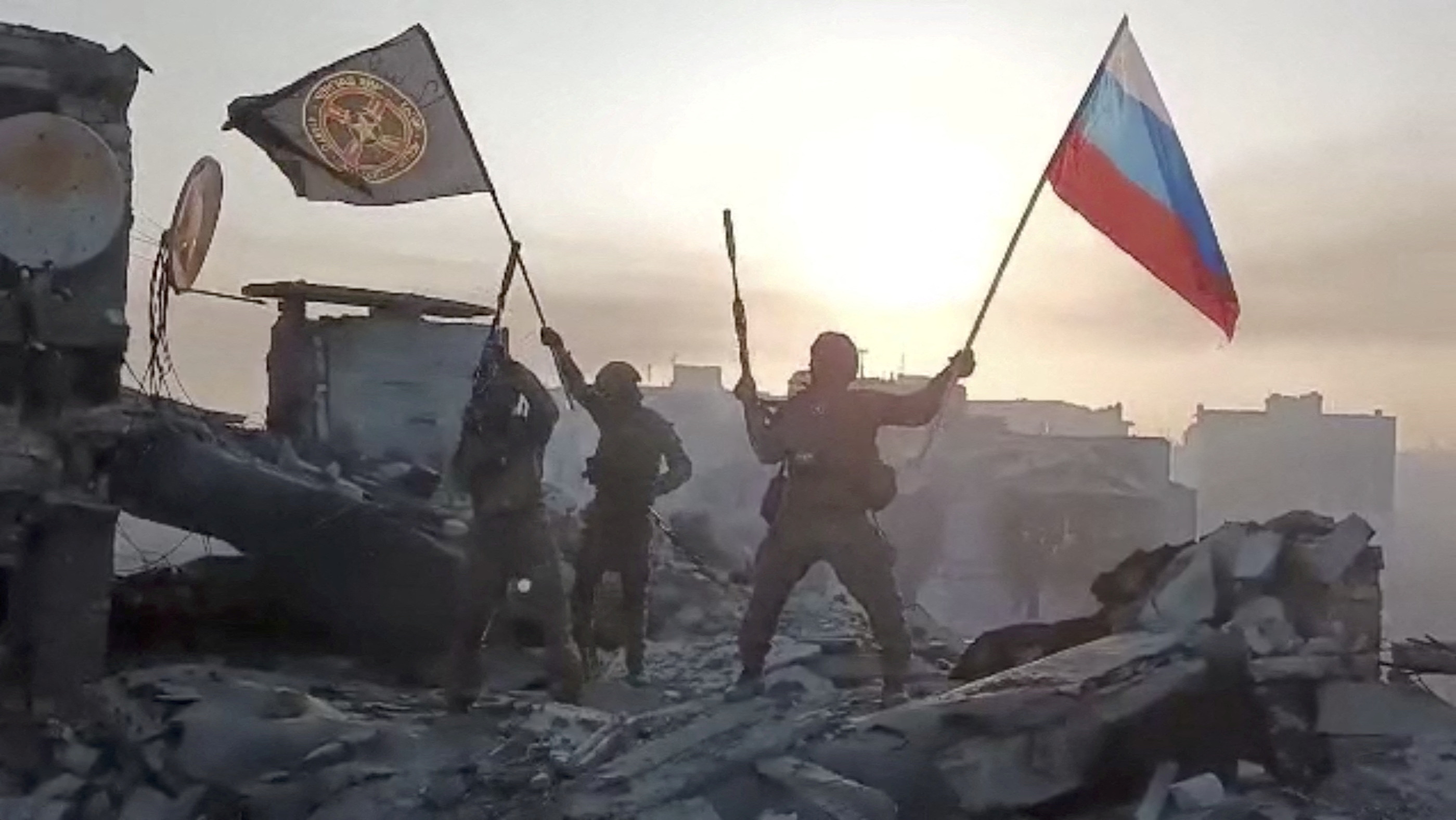 Wagner fighters wave flags of Russia and Wagner Group on top of a building in an unidentified location in this still image obtained from a video released on May 20, 2023, along with a statement by its chief Yevgeny Prigozhin about taking full control of Bakhmut