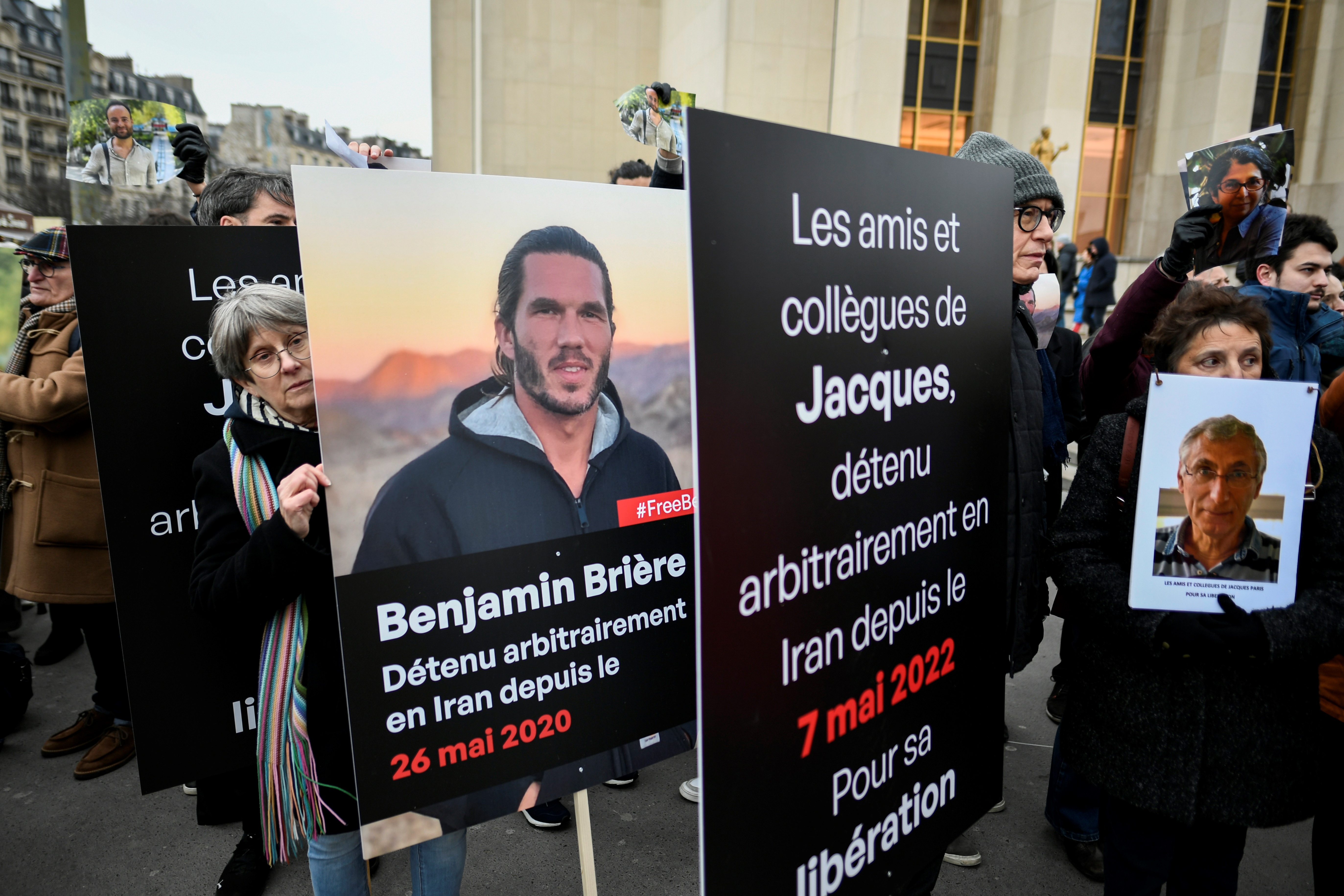Demonstrators hold photos of French detainees Benjamin Briere, left, and Jacques Paris