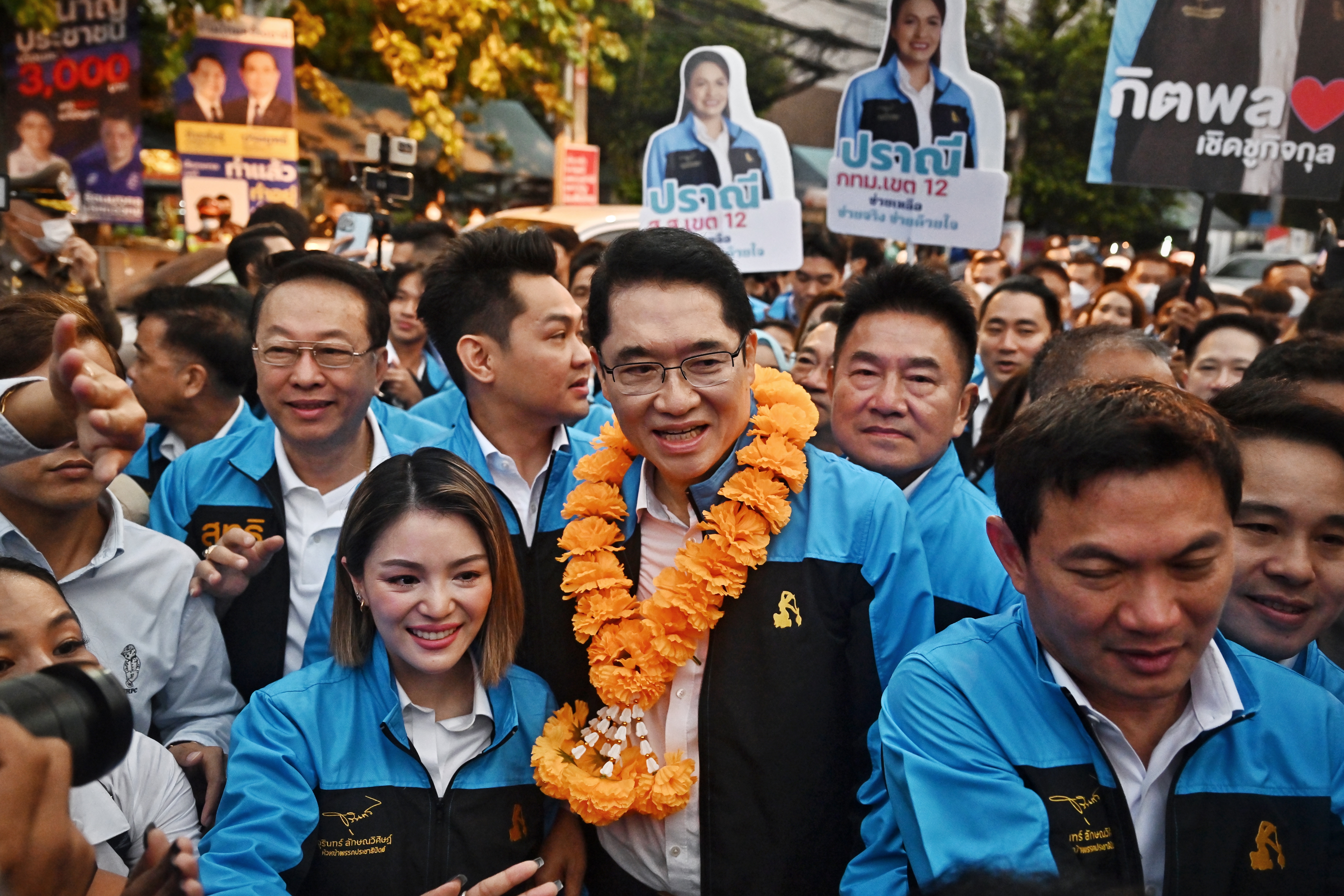 Jurin Laksanawisit, the leader of the Democrat party surrounded by supporters. He has a garland of golden marigolds around his neck. 