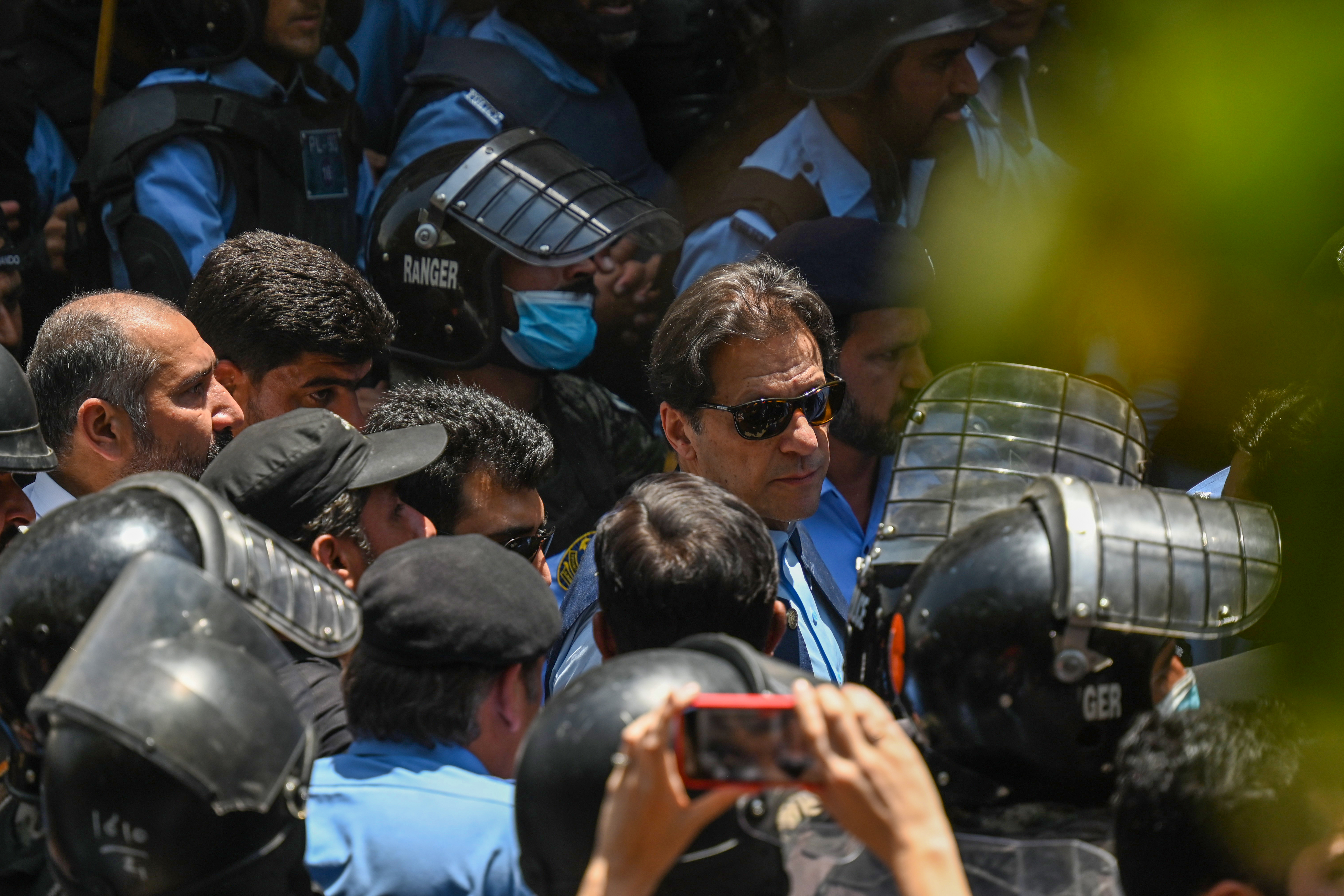 Policemen escort Pakistan's former Prime Minister Imran Khan (C) as he arrives at the high court in Islamabad on May 12, 2023.