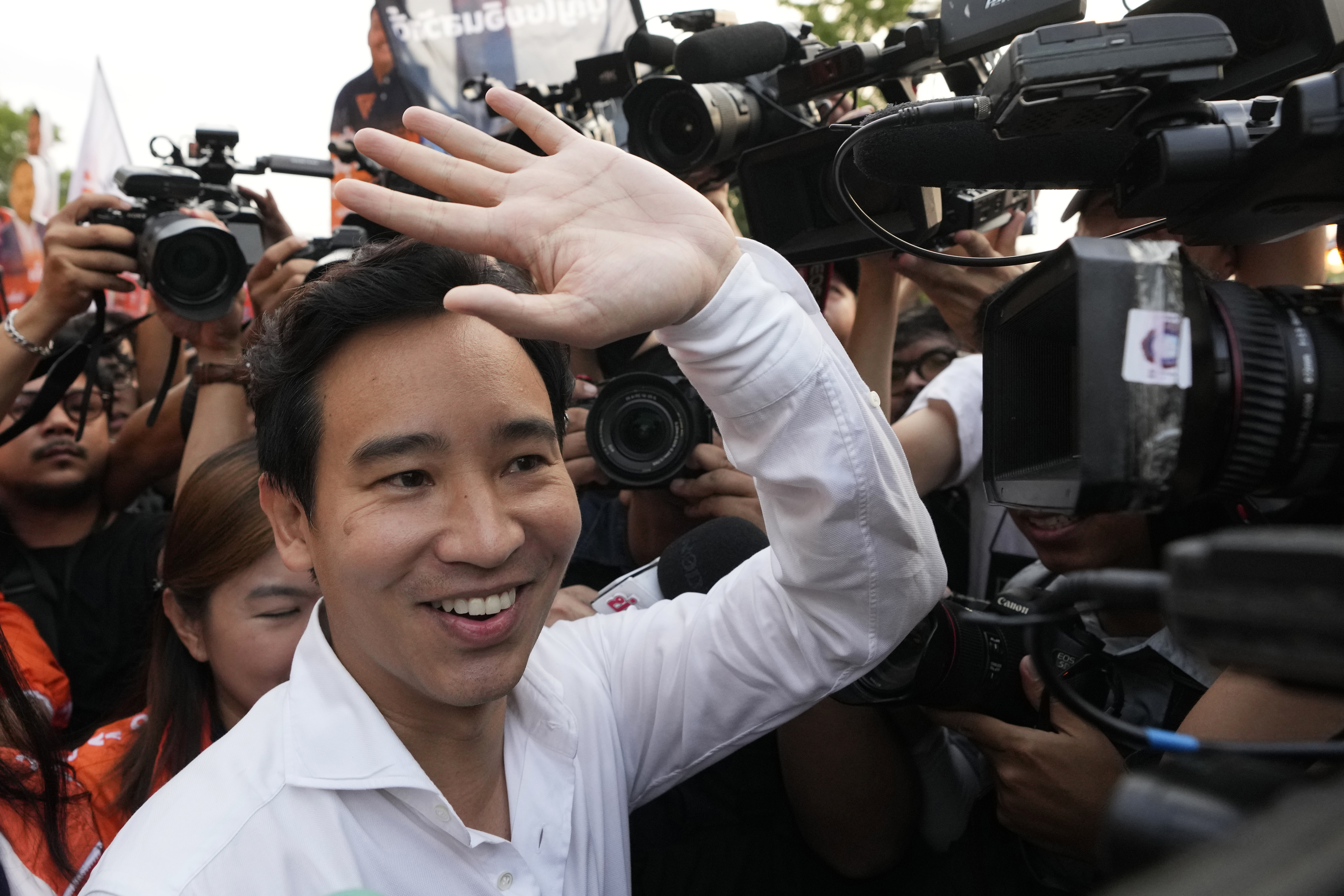 Pita Limjaroenrat waves to supporters. He is smiling and wearing a white shirt.