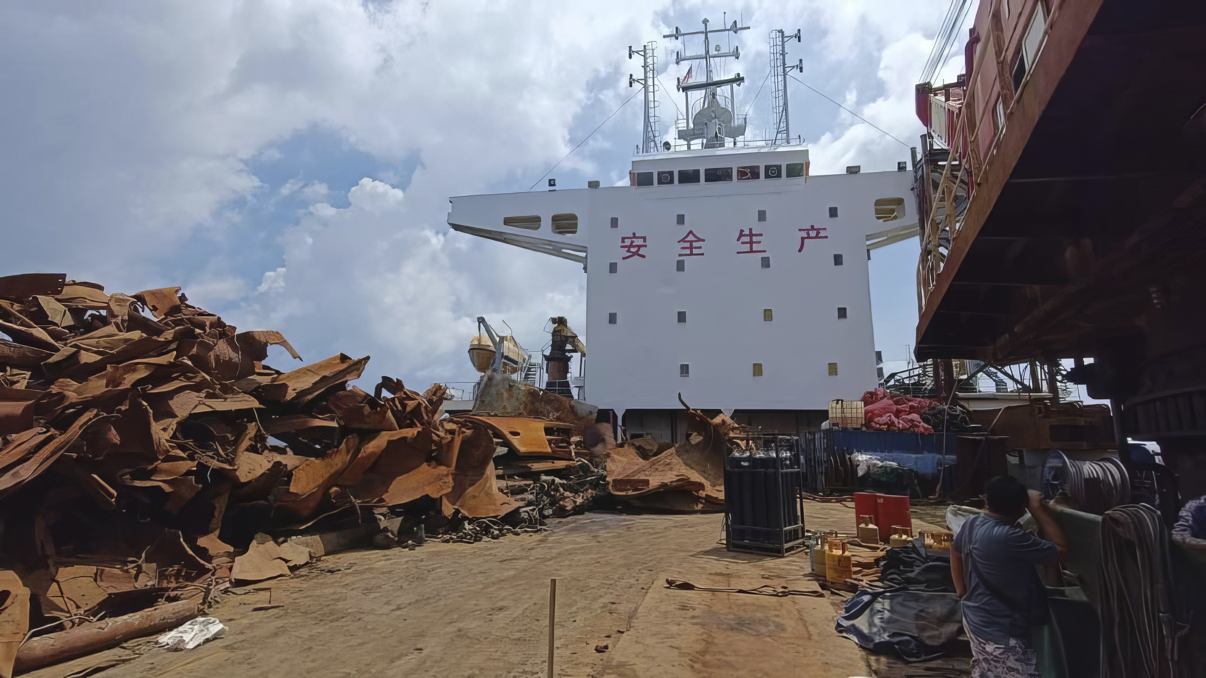 A view from the bow of the Chinese-registered vessel after it was seized. There is rusty scrap metal piled on the deck. The bridge is white and has Chinese characters painted in red across the top.