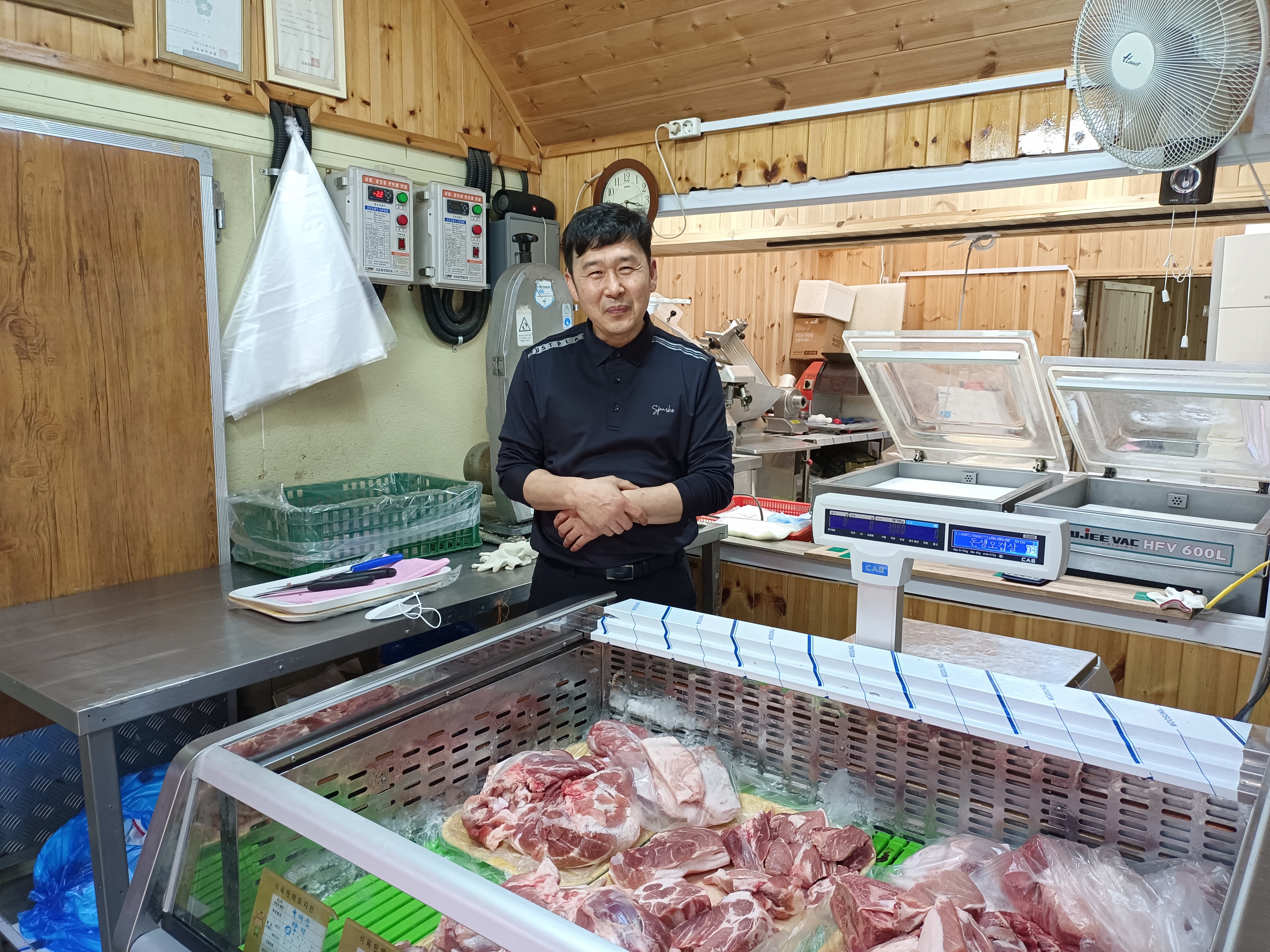 Choi Seong-ho smiling next to his meat fridge at the Daeryong Market at the North Korean border. 