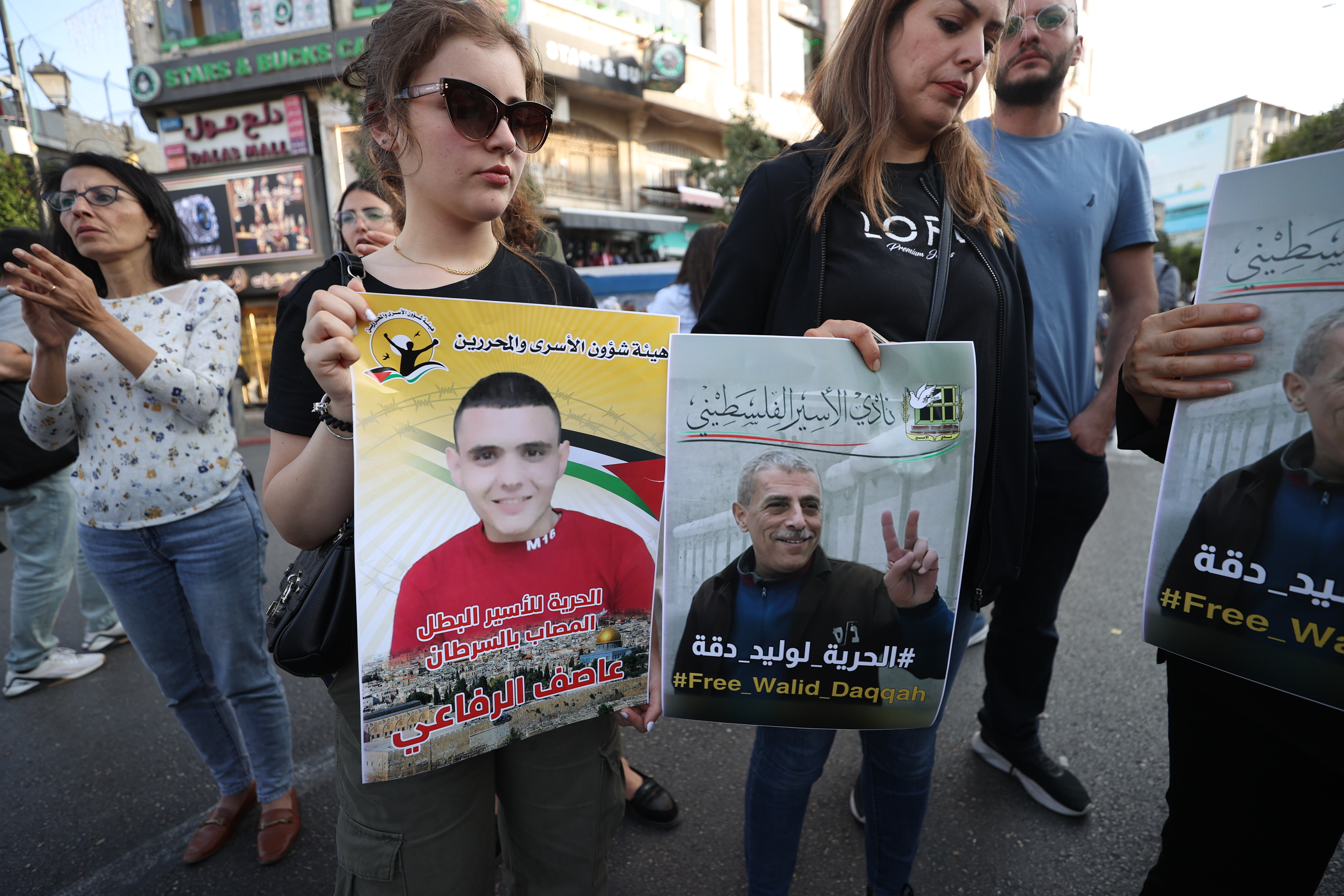 Palestinians hold up posters of Walid Daqqa and another ill prisoner Asef al-Rifai who also suffers from cancer [Al Jazeera]