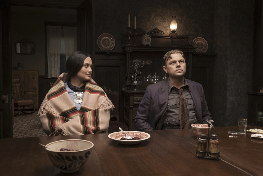 Lily Gladstone and Leonardo DiCaprio sit at a table