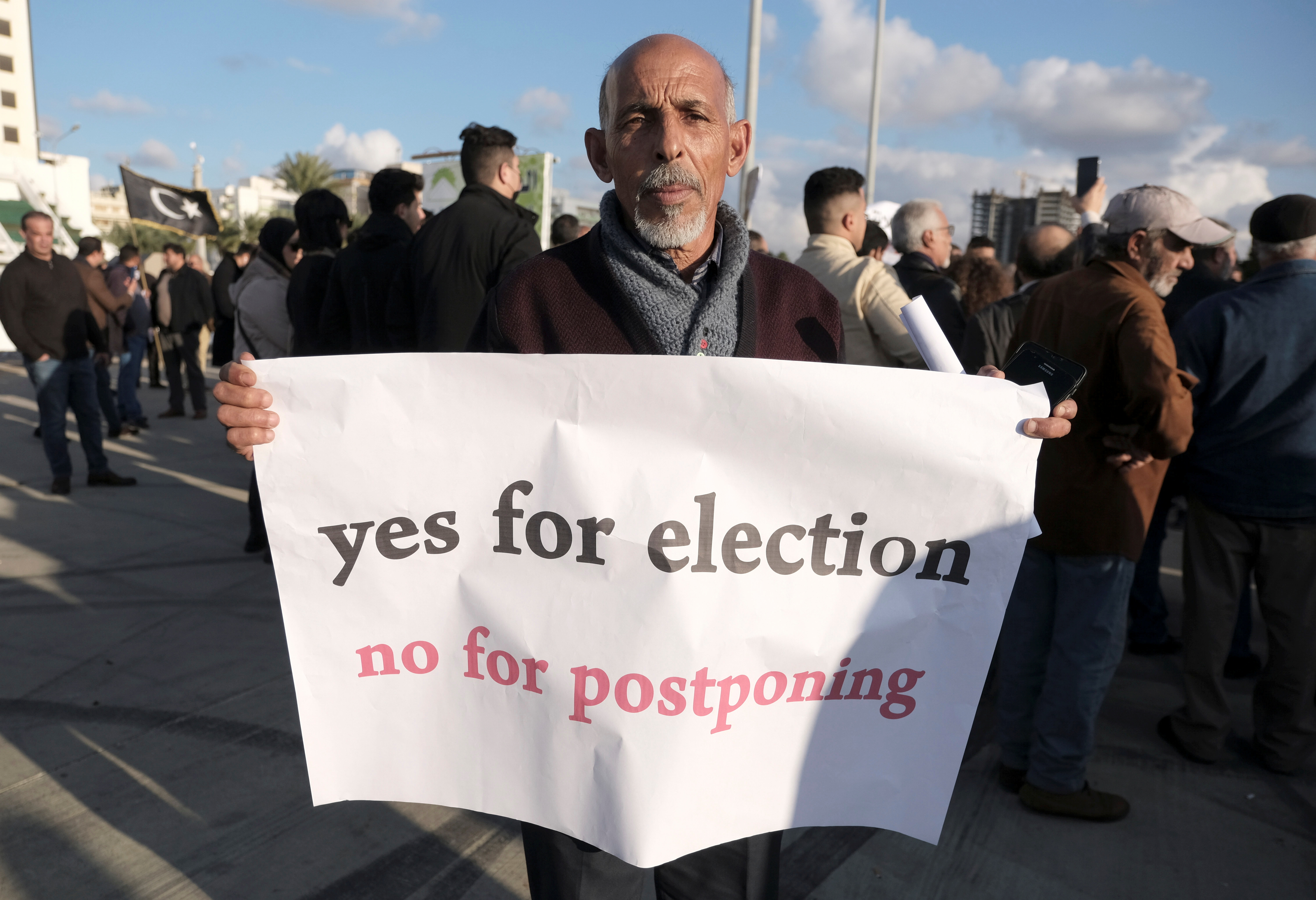 A man holds a banner during a protest against the delay to the Libyan presidential election