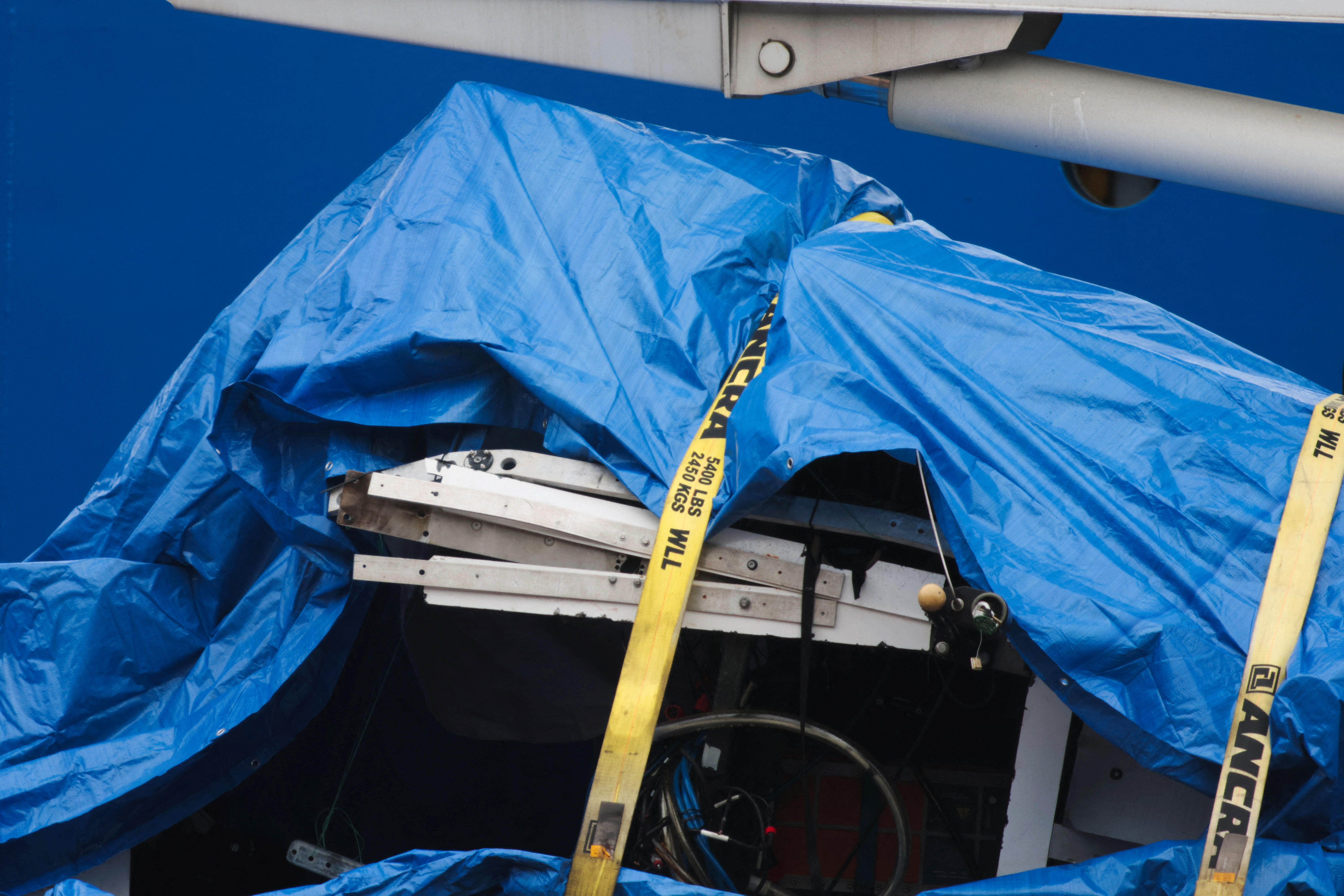Pieces of the destroyed Titan submersible are covered by a tarp as they are unloaded to St John’s, Newfoundland, on Wednesday