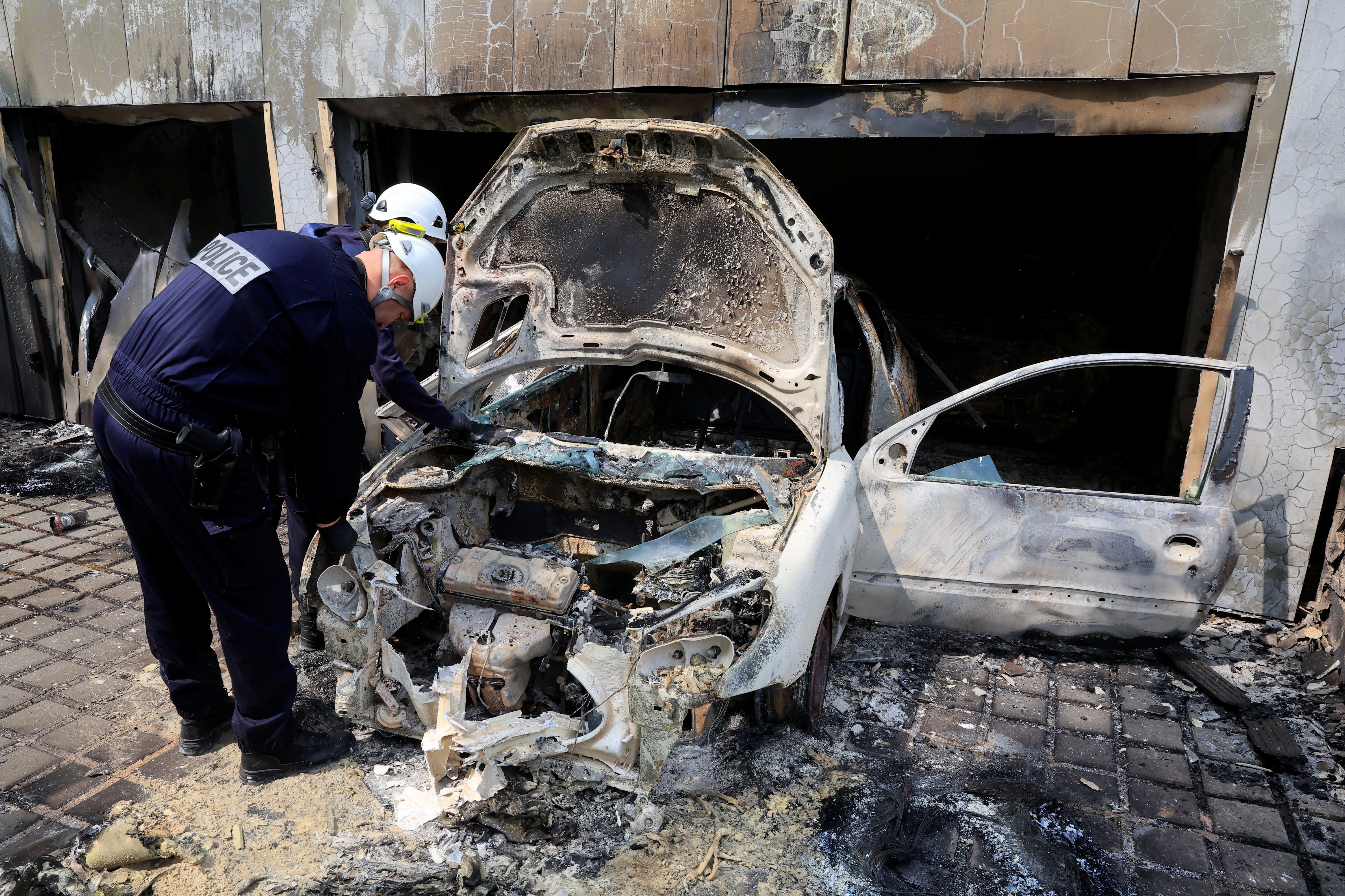 French police inspect a municipal police car, burnt during night clashes between protesters and police, following the death of Nahel, a 17-year-old teenager killed by a French police officer in Nanterre during a traffic stop, at a police station in Mons-en-Baroeul, near Lille, northern France, June 29, 2023. REUTERS/Pascal Rossignol