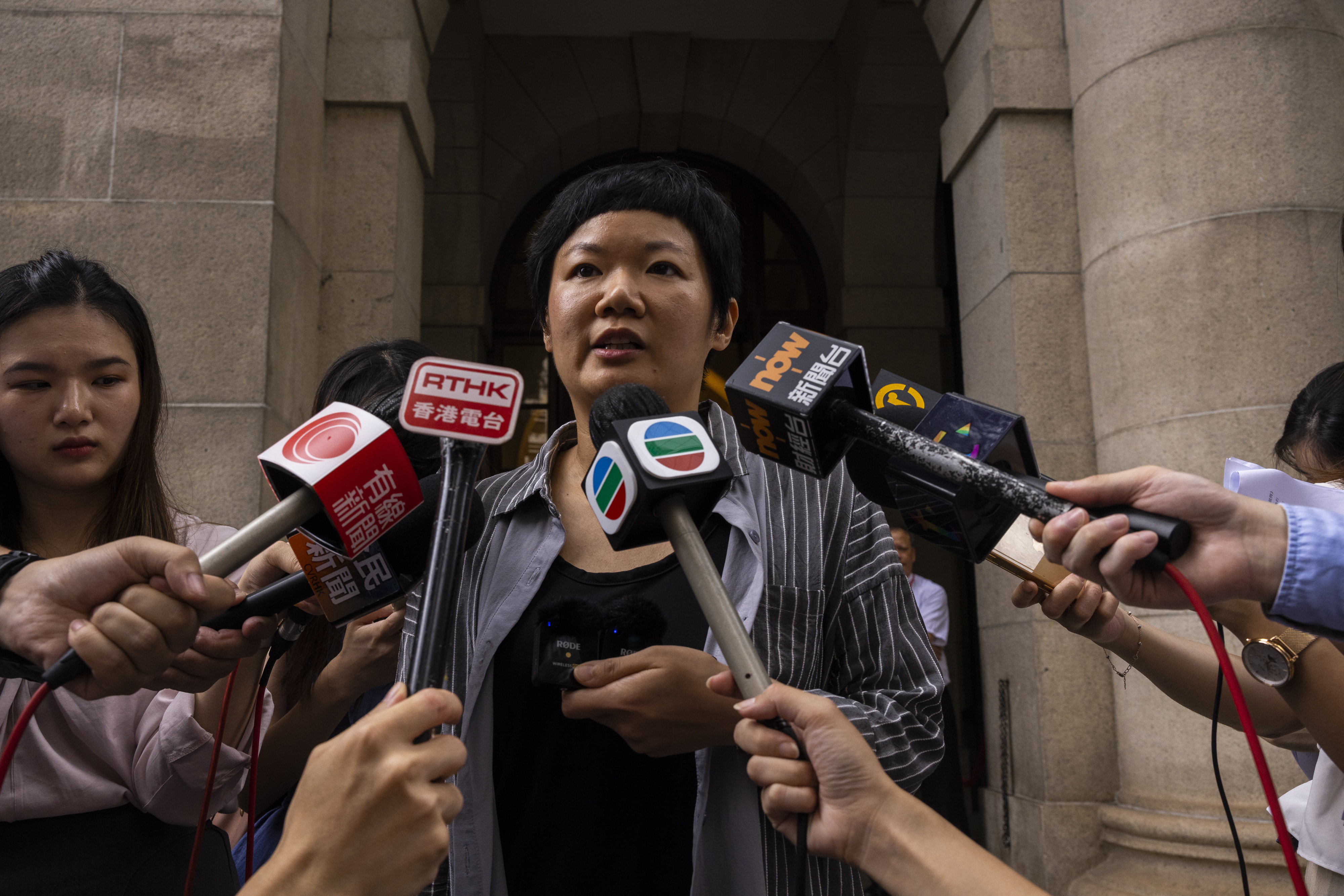 Journalist Bao Choy speaking outside Hong Kong's top court after she was cleared. She is surrounded by microphones held out by local journalists