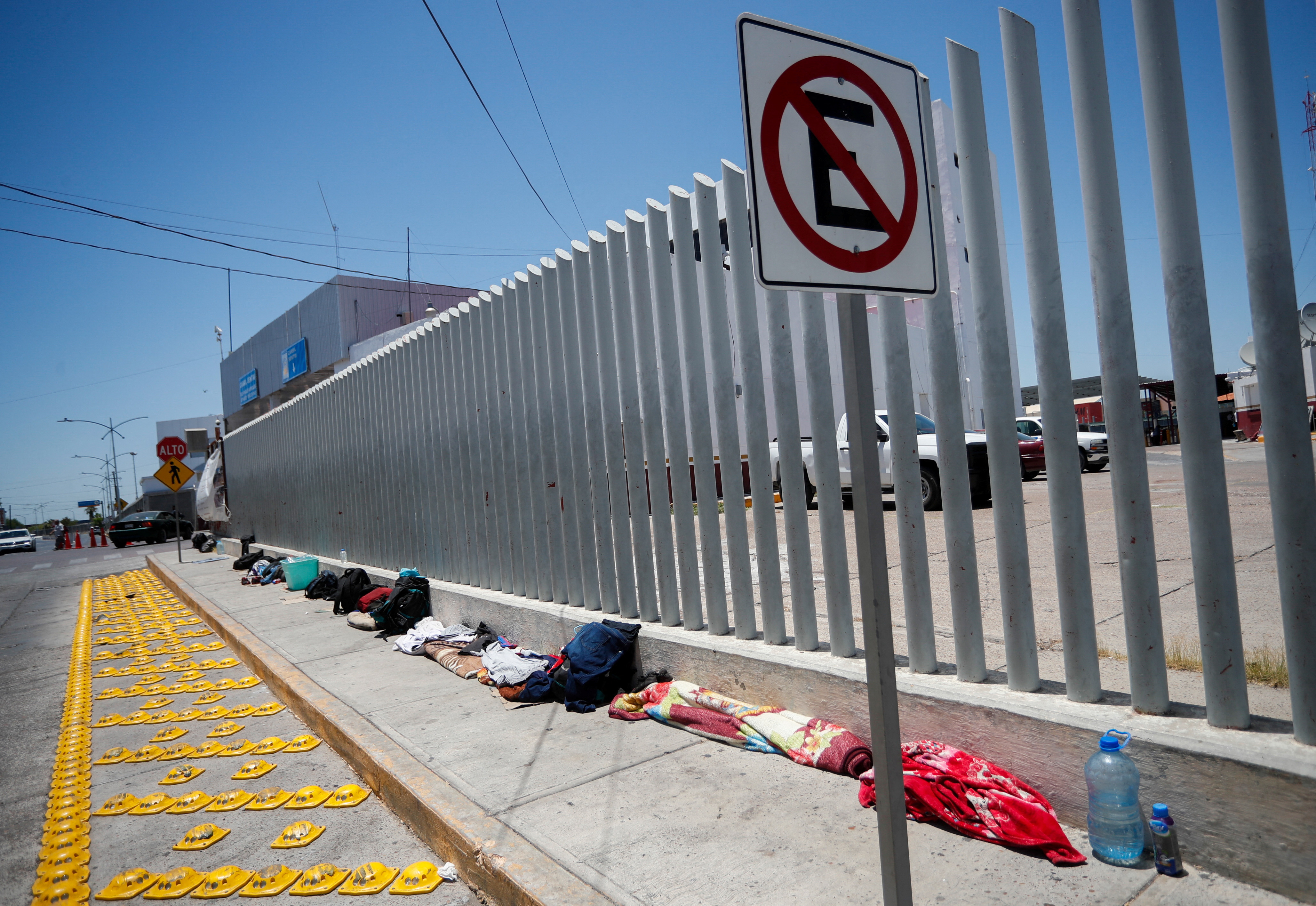 Blankets and bags form a line along a border fence.