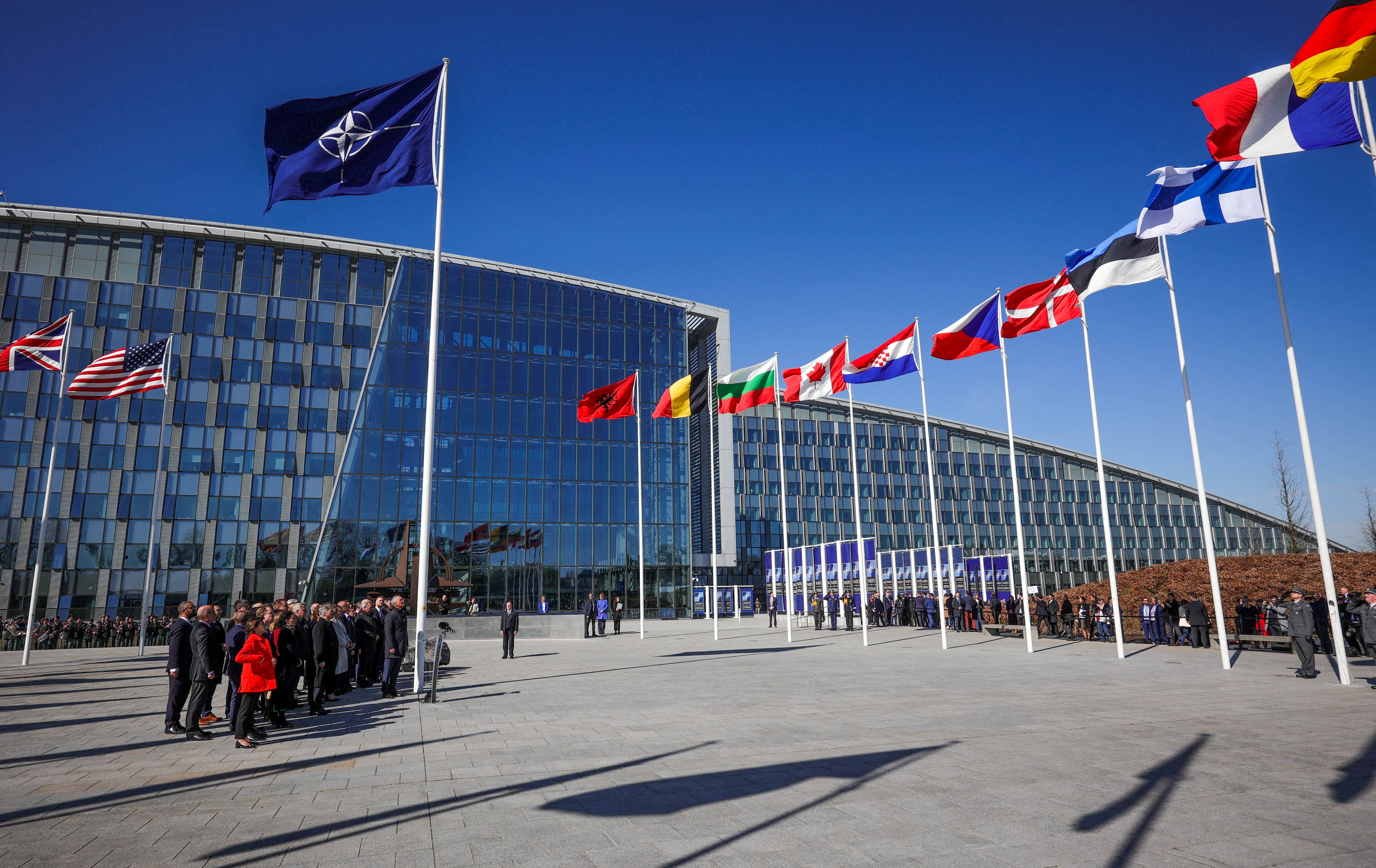 Officials attend a flag-raising ceremony for Finland's accession during NATO foreign ministers' meeting