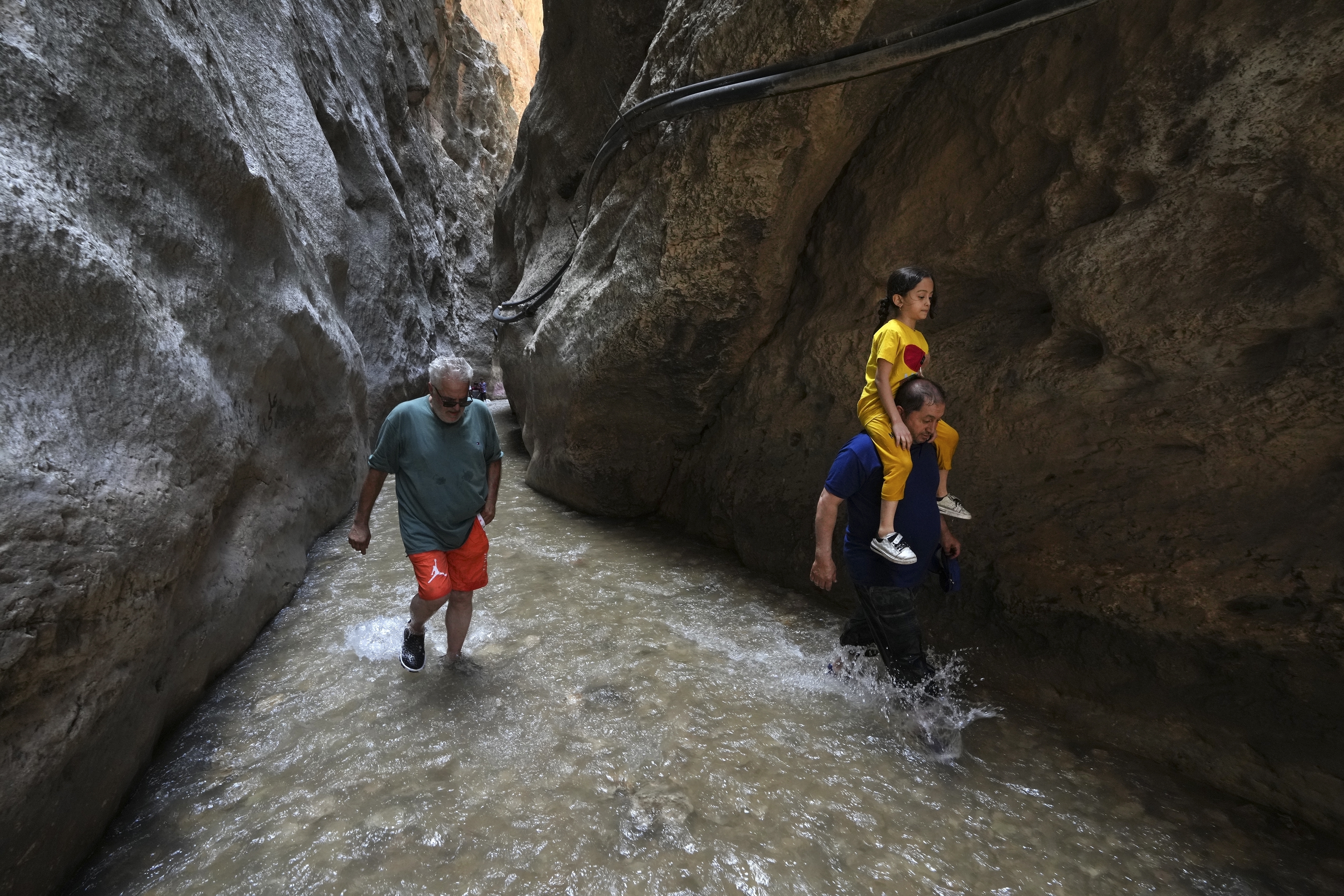 People walk in a cold mountain river