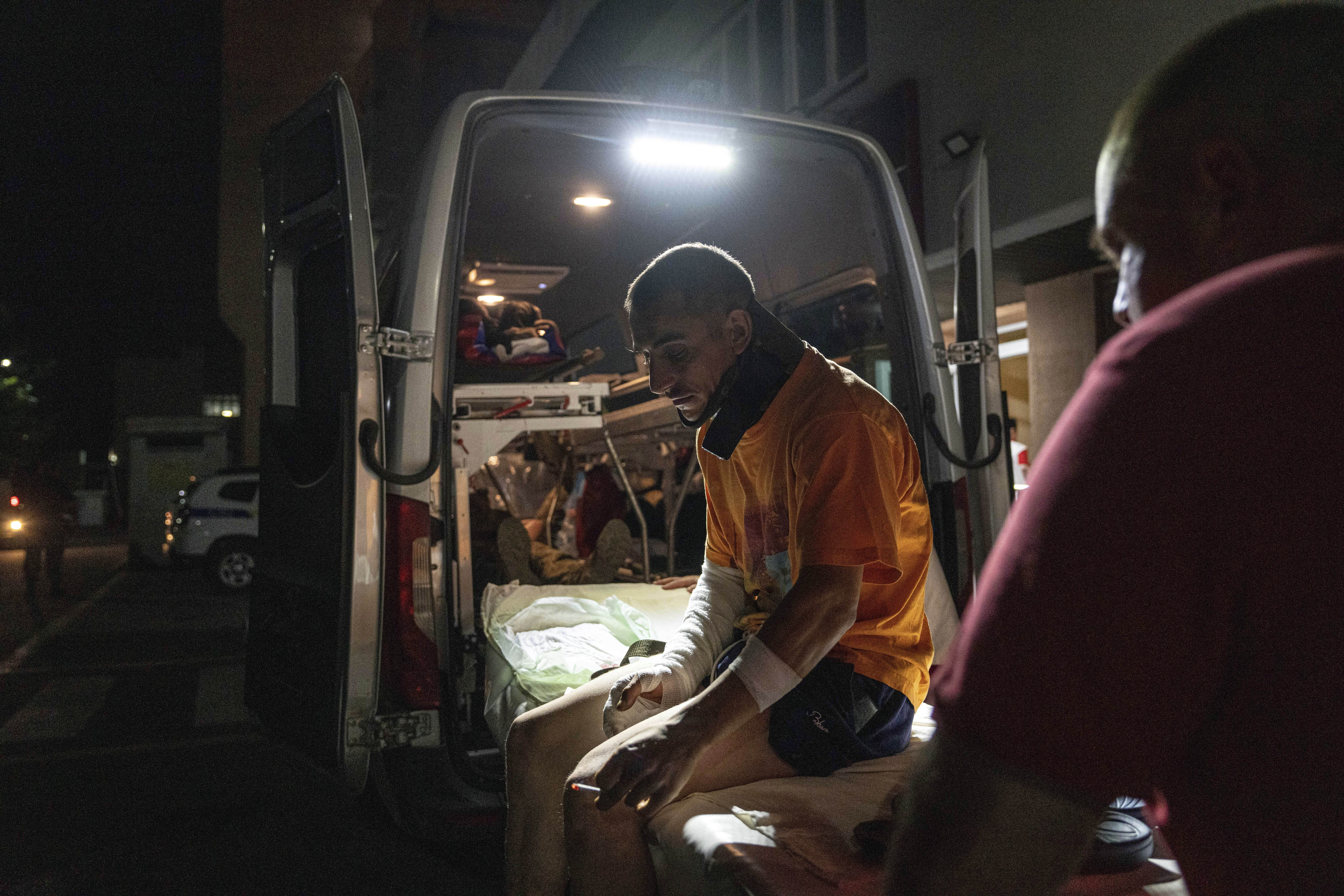A wounded Ukrainian serviceman smokes a cigarette outside an ambulance