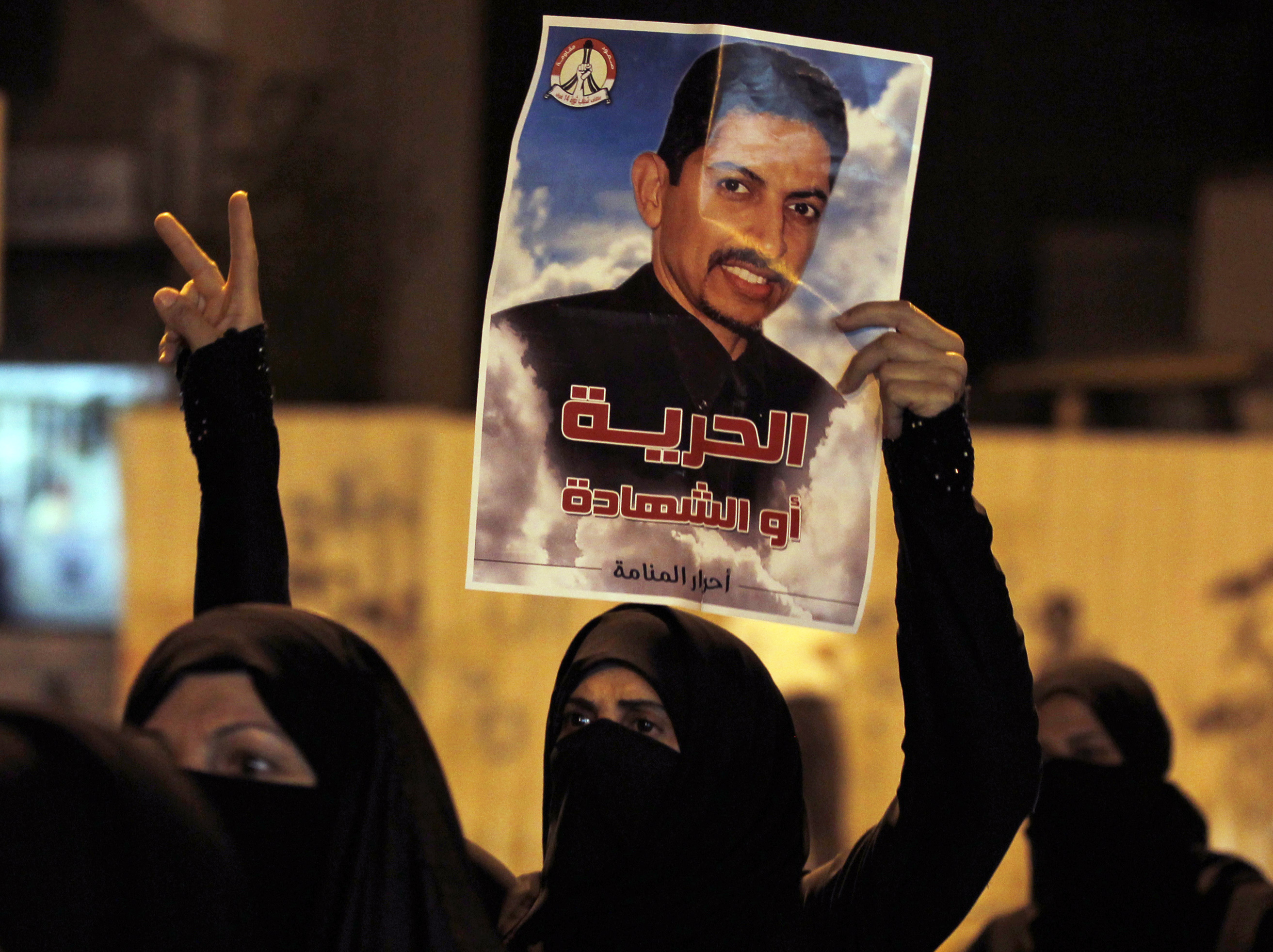 A protester holds a poster of Human Rights Activists Abdulhadi al-Khawaja during an anti-government rally