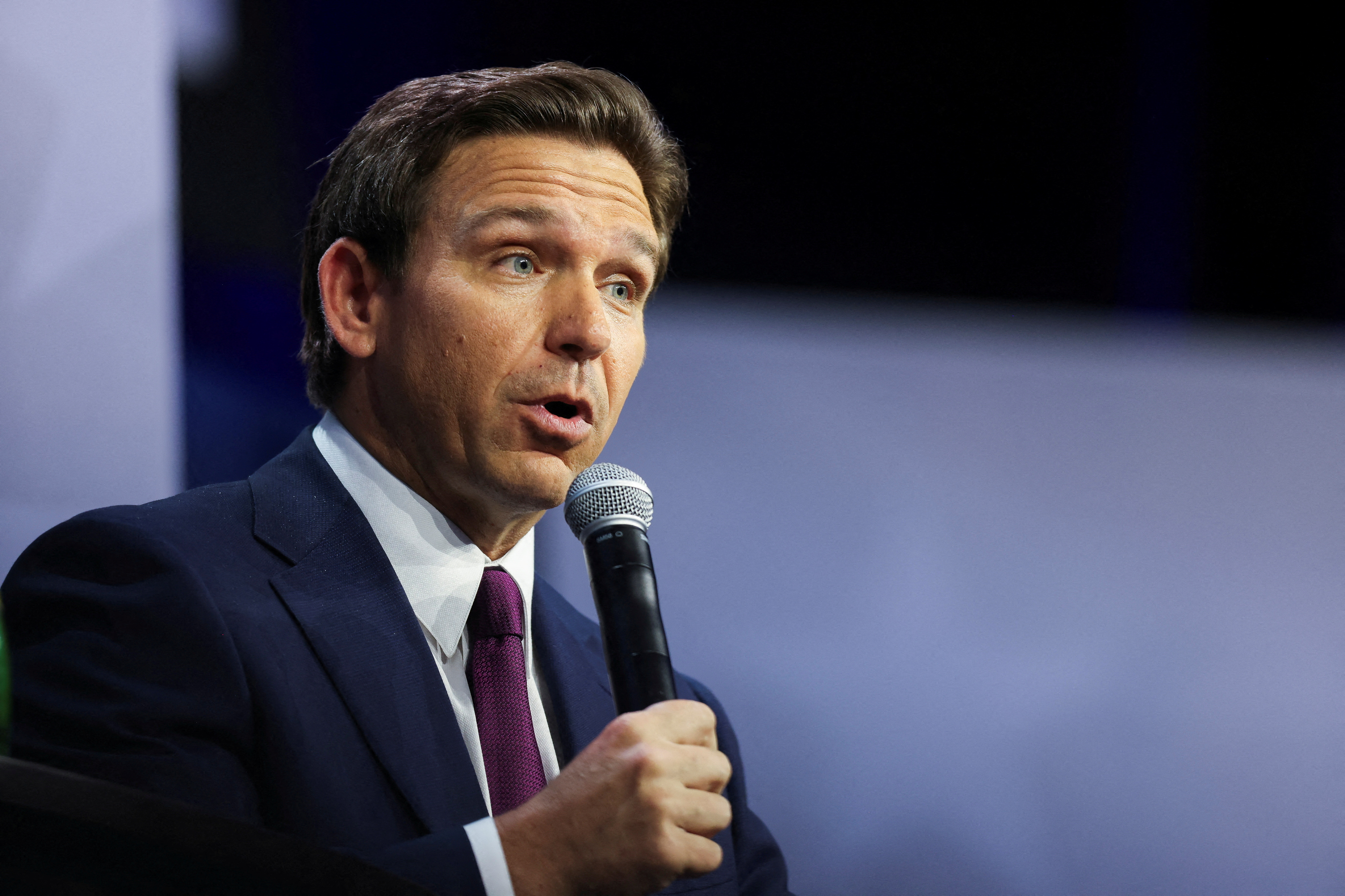Florida Governor Ron DeSantis holds a microphone