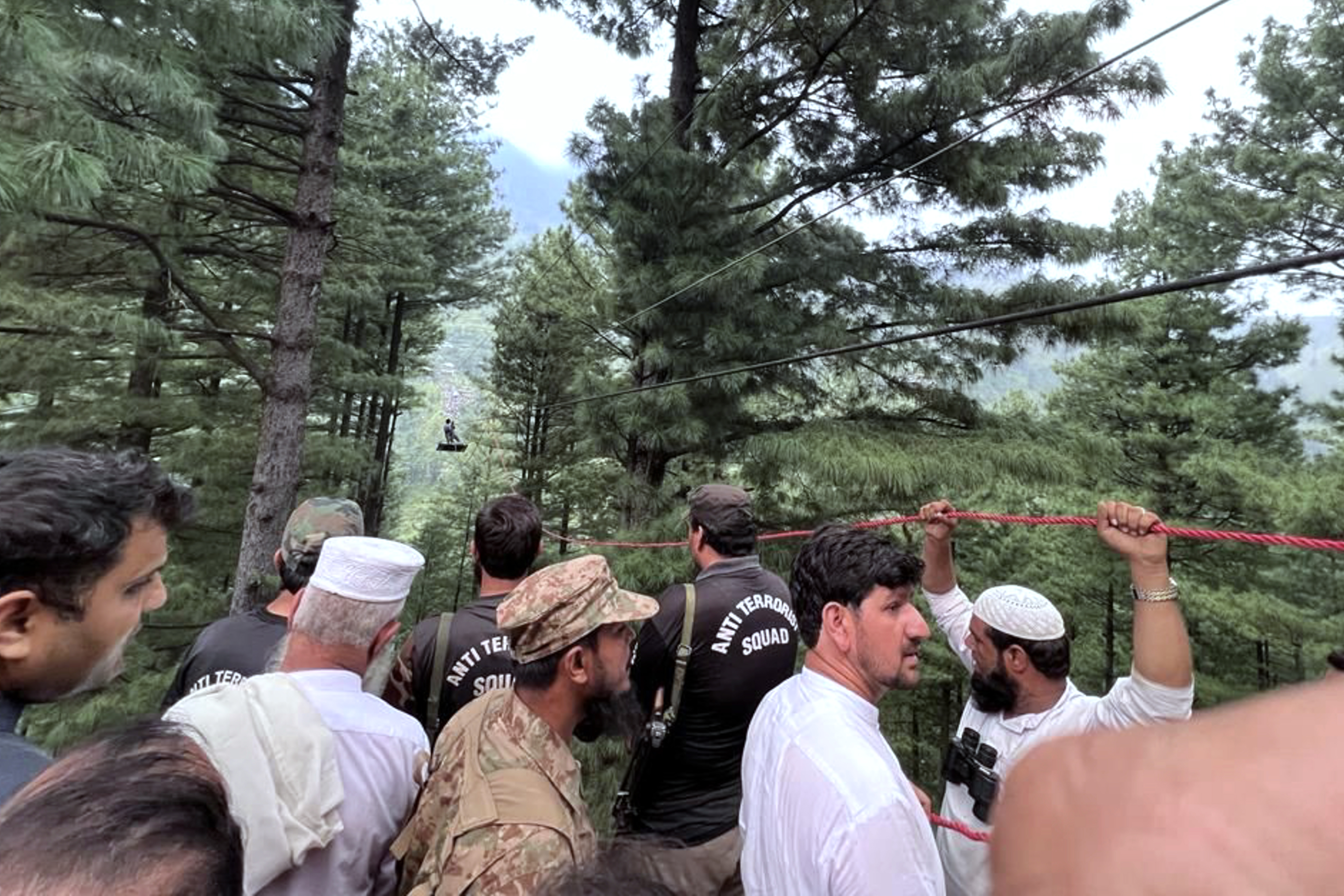 This handout photograph taken on August 22, 2023 and released by the Pakistan's Inter Service Public Relation (ISPR) shows an army soldier (top) rescueing a student survivor, who was trapped in a cable car following an incident, in Pashto village, northwestern Pakistan. - Military helicopters and zipline experts rescued eight people, including six school boys, trapped for hours in a stricken cable car high above a remote Pakistan valley. (Photo by Handout / ISPR / AFP) / RESTRICTED TO EDITORIAL USE - MANDATORY CREDIT "AFP PHOTO/PAKISTAN'S INTER SERVICE PUBLIC RELATION (ISPR)" - NO MARKETING NO ADVERTISING CAMPAIGNS - DISTRIBUTED AS A SERVICE TO CLIENTS - RESTRICTED TO EDITORIAL USE - MANDATORY CREDIT "AFP PHOTO/PAKISTAN'S INTER SERVICE PUBLIC RELATION (ISPR)" - NO MARKETING NO ADVERTISING CAMPAIGNS - DISTRIBUTED AS A SERVICE TO CLIENTS /