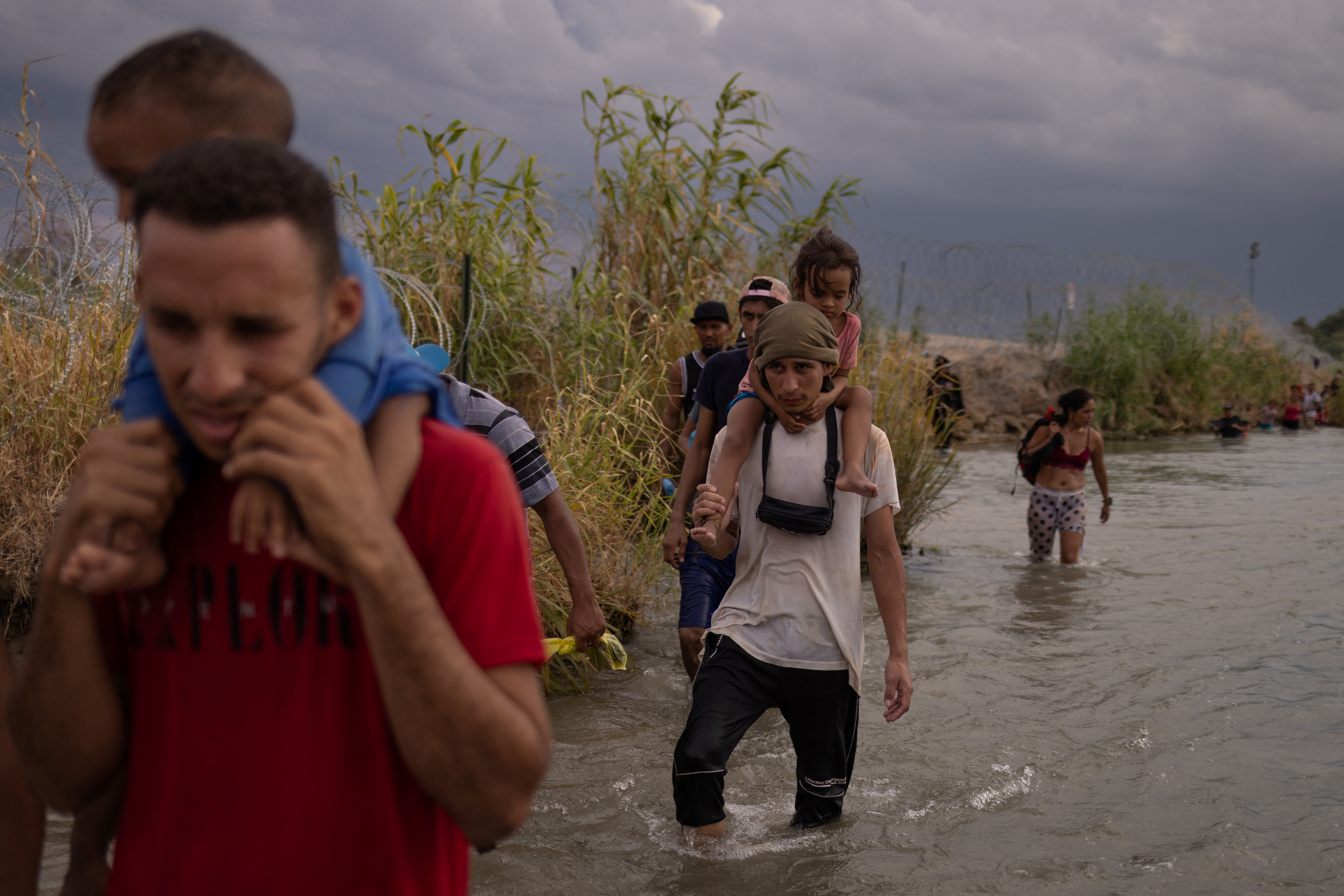 Davey, a 20-year-old from Venezuela, carries three-year-old Lilliana on his shoulders as he crosses through the Rio Grande near Eagle Pass, Texas, on September 15