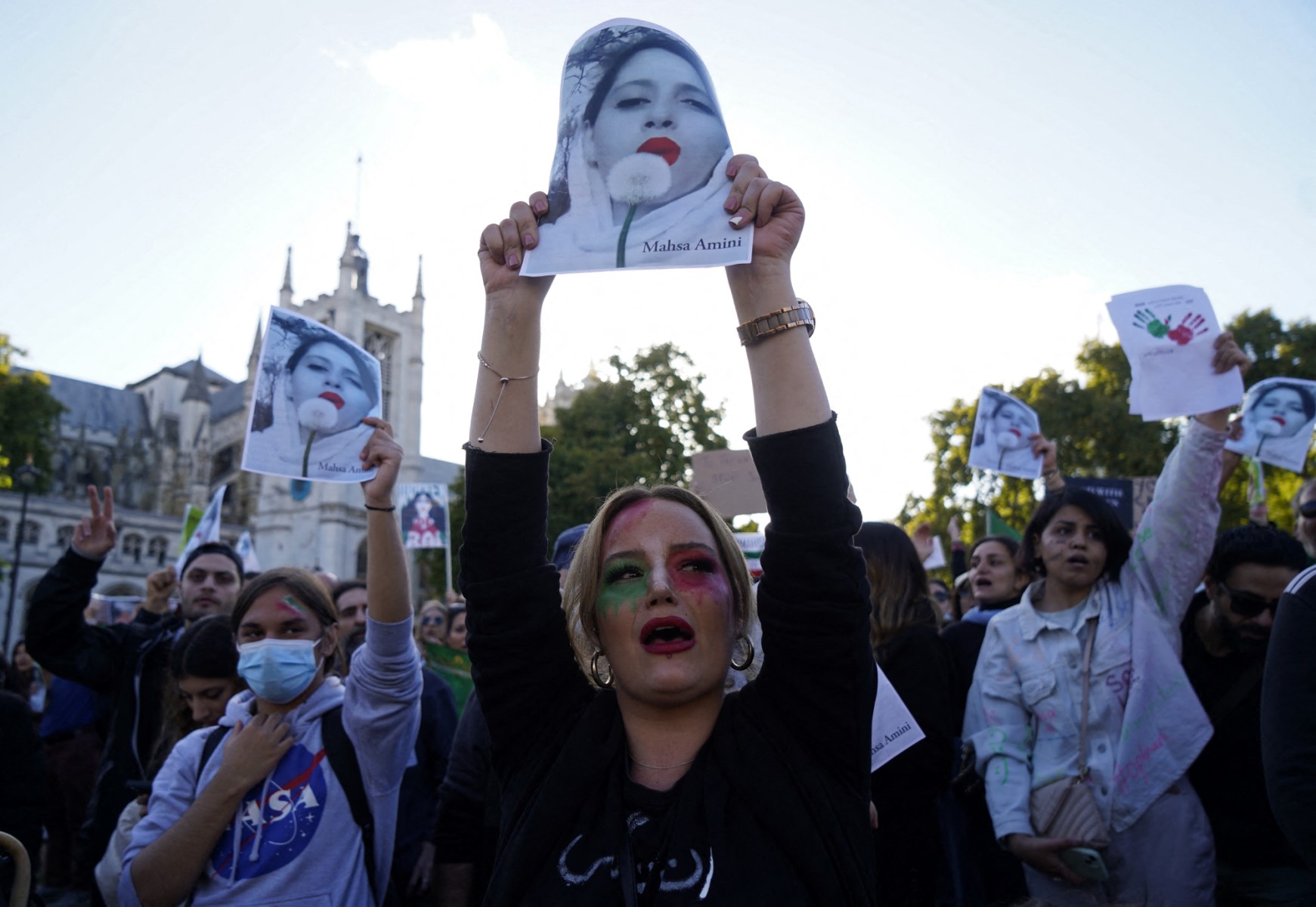 People chant slogans and hold the pictures of Mahsa Amini during a demonstration in central London on October 8, 2022. Amini, 22, died on September 16, three days after falling into a coma following her arrest by Iran's morality police for allegedly breaching the Islamic republic's strict dress code for women.