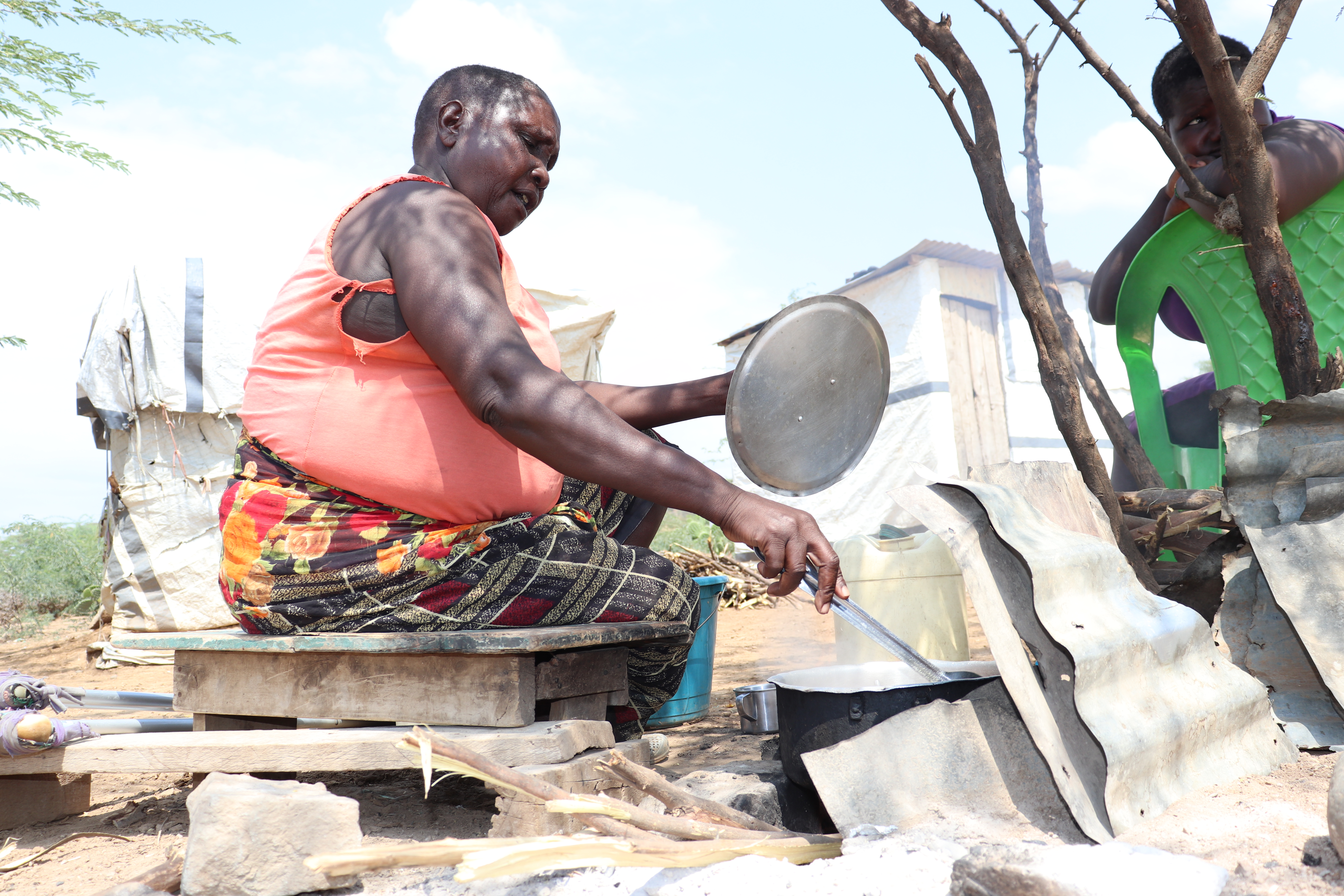 Ruma Naiweti, 59, prepares lunch outside her tent at Kiwanja Ndege in Baringo County, Kenya