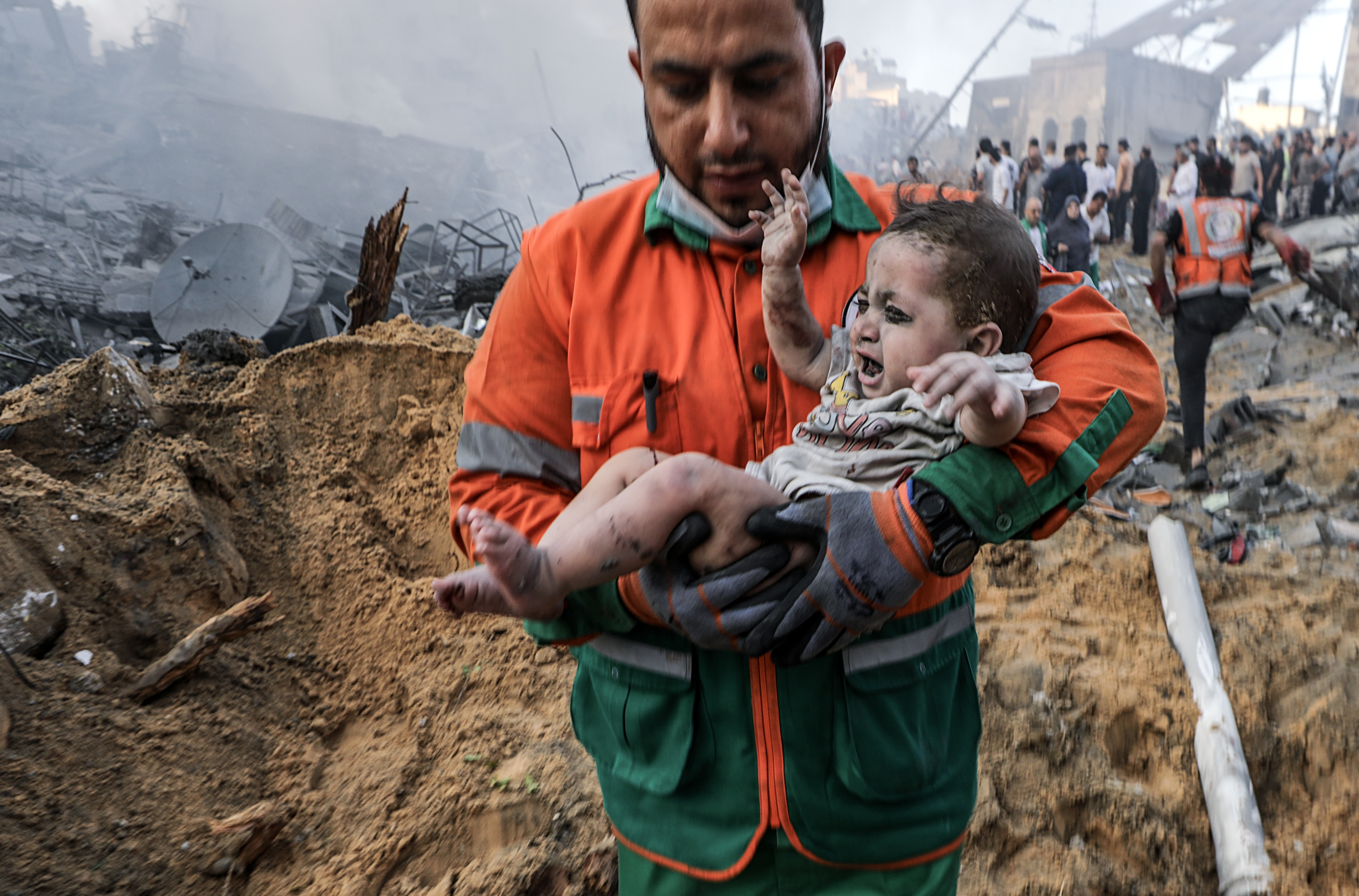 A Palestinian man carries a wounded baby that he recovered from the rubble of a destroyed area following Israeli air strikes in Gaza City