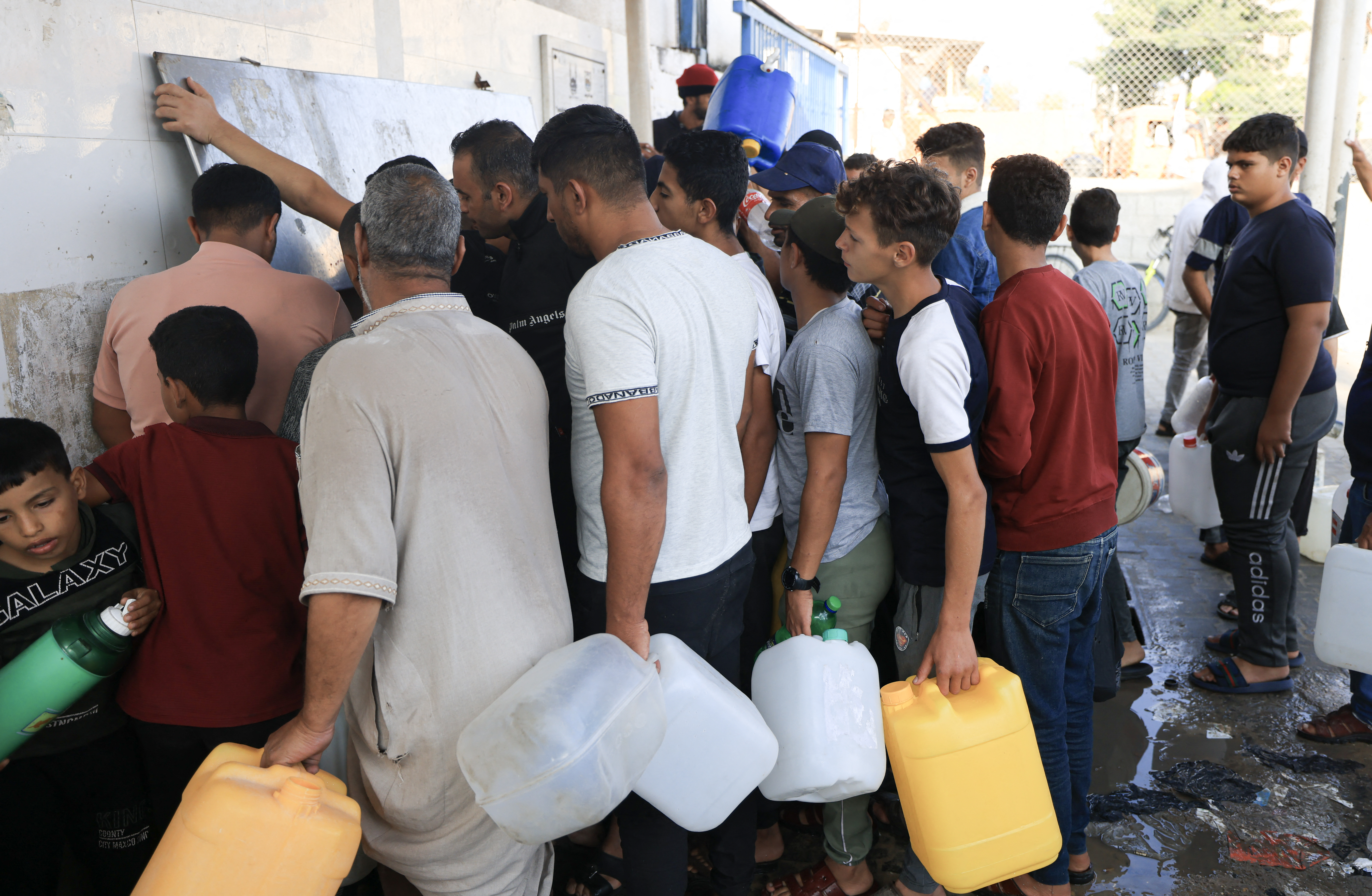 Palestinians queue to fill containers with water in Khan Yunis in the southern Gaza Strip on October 14, 2023
