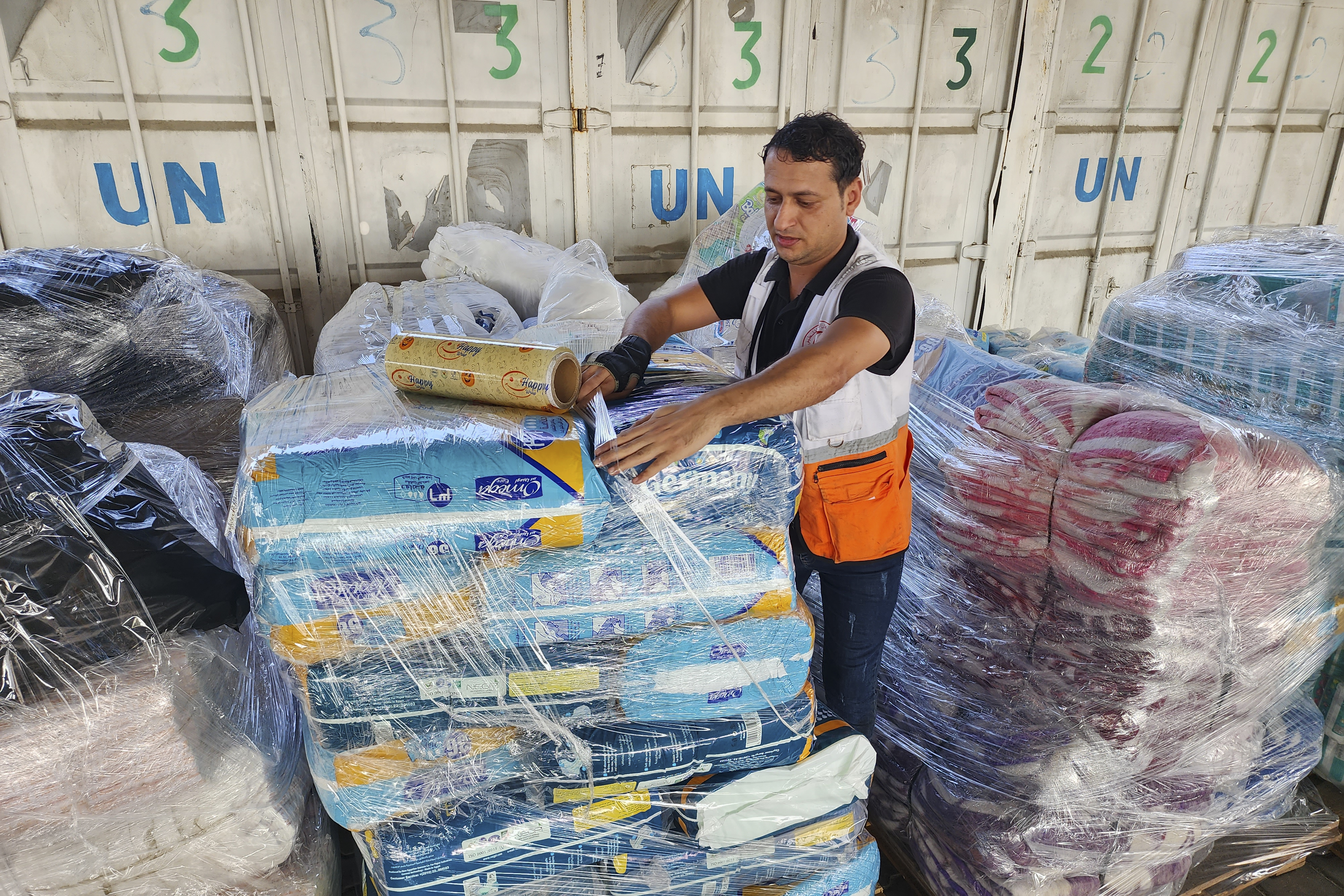 United Nations and Red Crescent workers prepare the aid for distribution to Palestinians at UNRWA warehouse in Deir Al-Balah