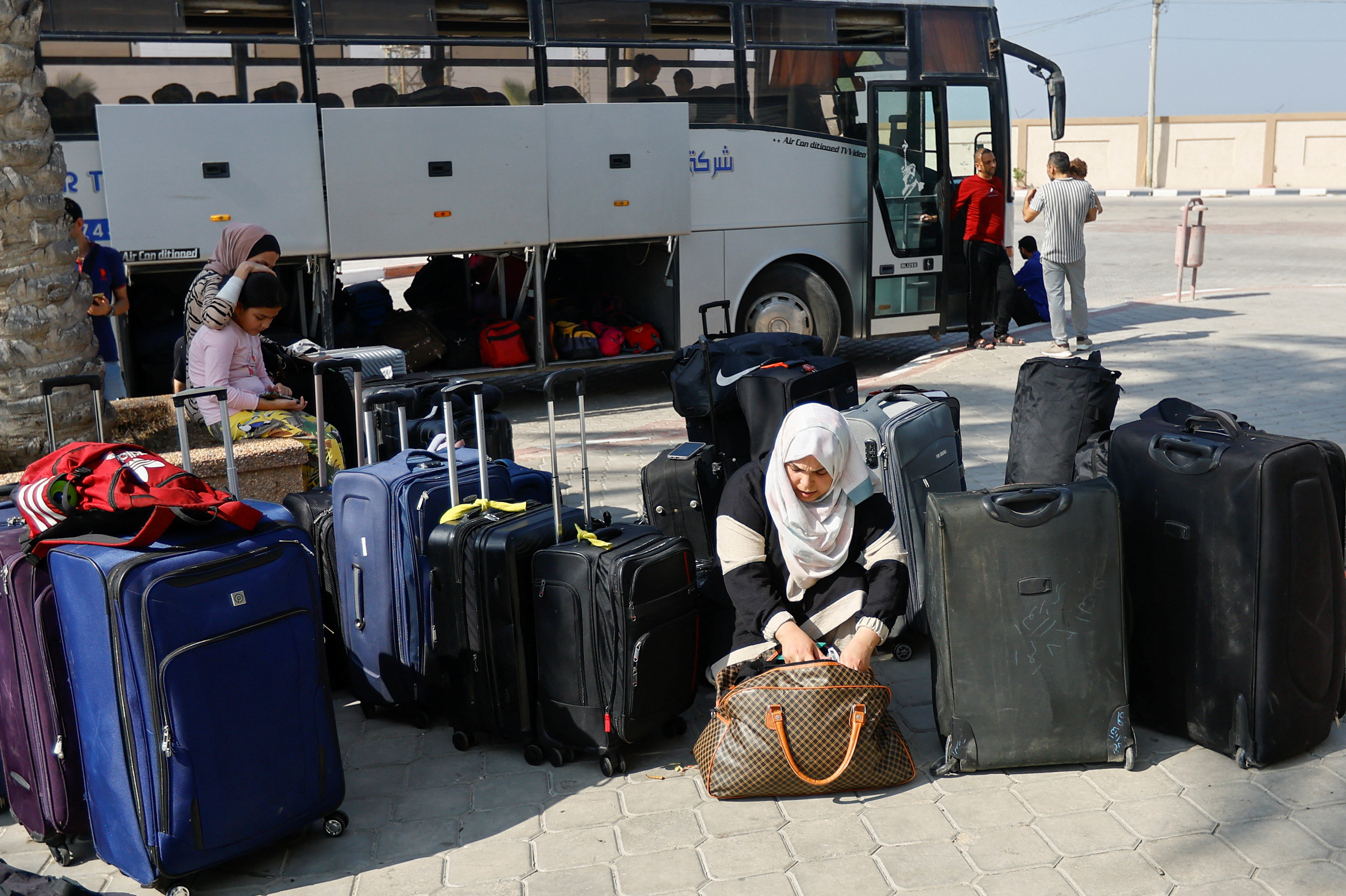 A Palestinian holding a foreign passport looks through her bag as she waits for permission to leave Gaza, amid the continuing conflict between Israel and Hamas, at the Rafah border crossing with Egypt in the southern Gaza Strip on November 3, 2023