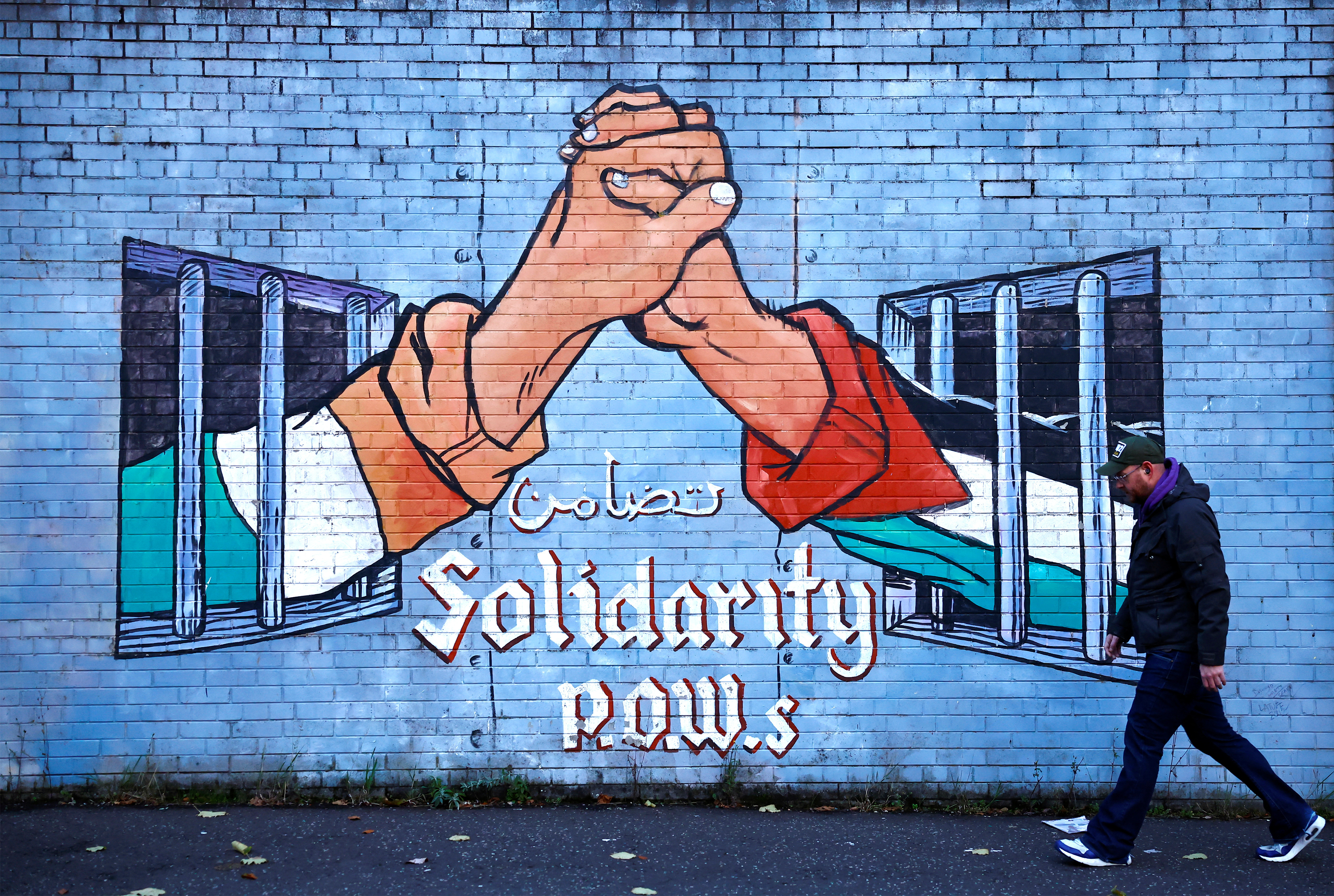 A man walks past a mural in solidarity with Palestinians in Gaza, amid the ongoing conflict between Israel and Hamas, in the Nationalist area along the International Wall on the Falls Road in Belfast, Northern Ireland, November 4, 2023. REUTERS/Clodagh Kilcoyne