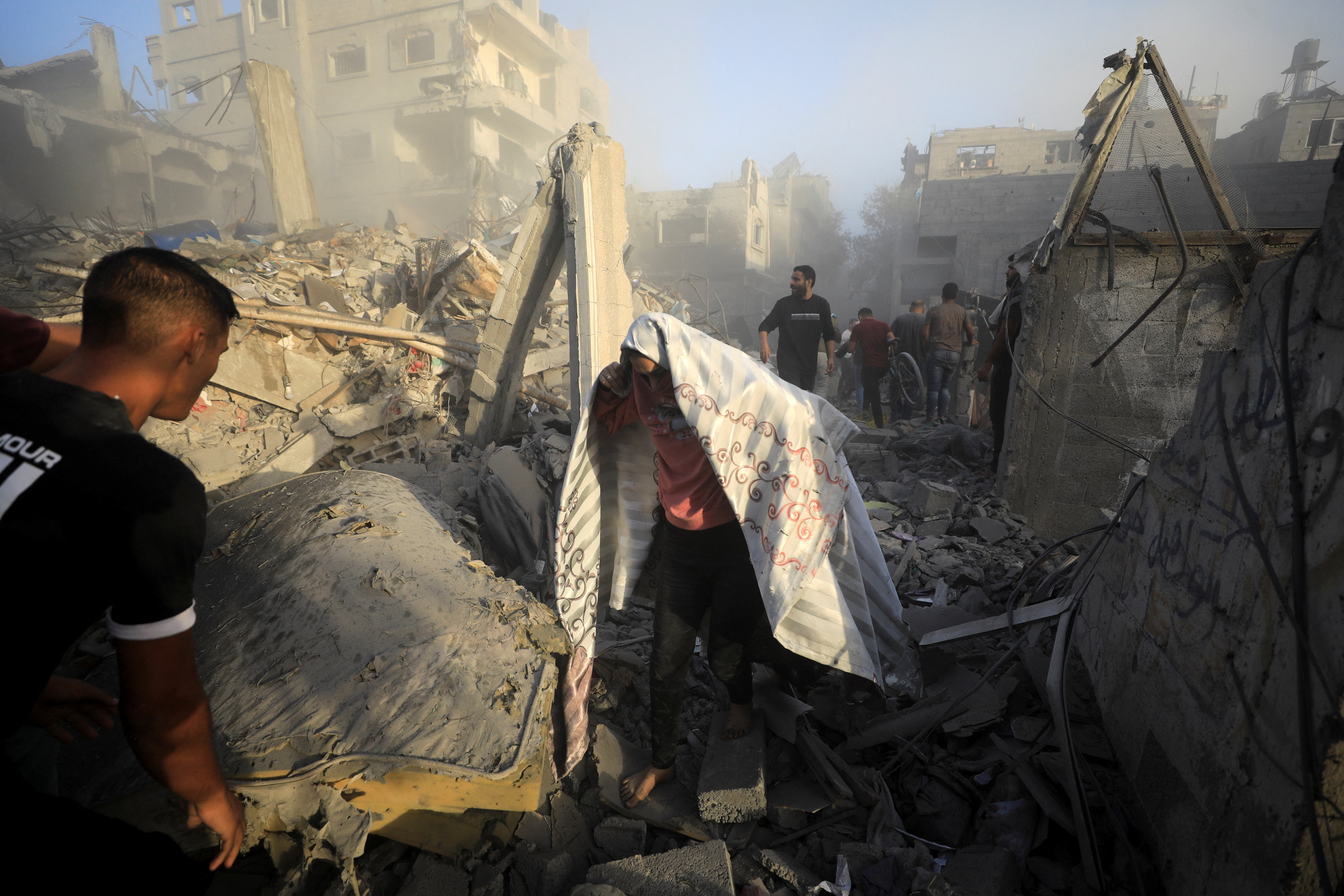 Palestinians evacuate the site of Israeli strikes on houses, amid the ongoing conflict between Israel and Palestinian Islamist group Hamas, in Maghazi refugee camp in the central Gaza Strip