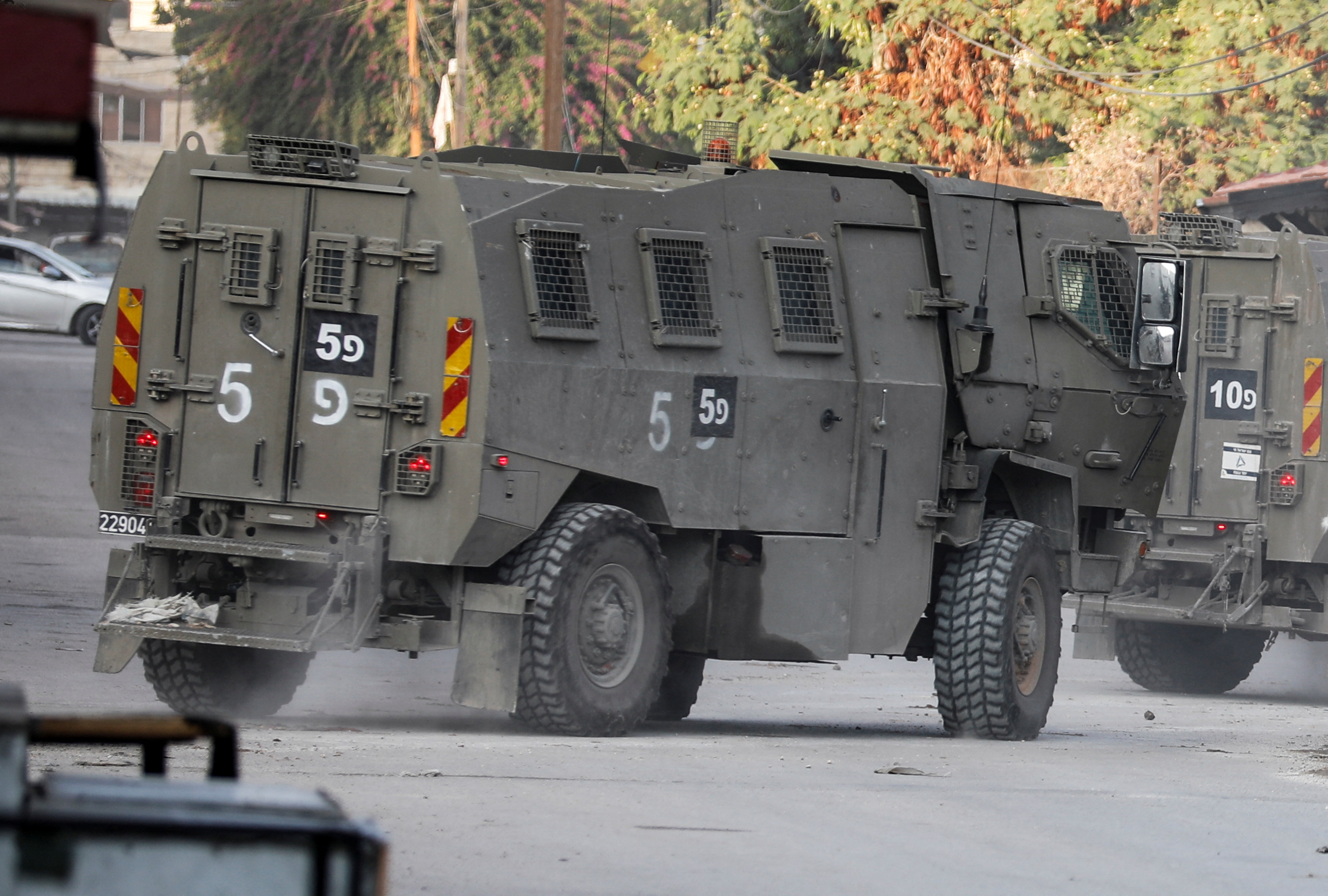 Israeli military vehicles move through a street after Israeli forces raided the Jenin refugee camp in the Israeli-occupied West Bank, November 17, 2023. REUTERS/Raneen Sawafta