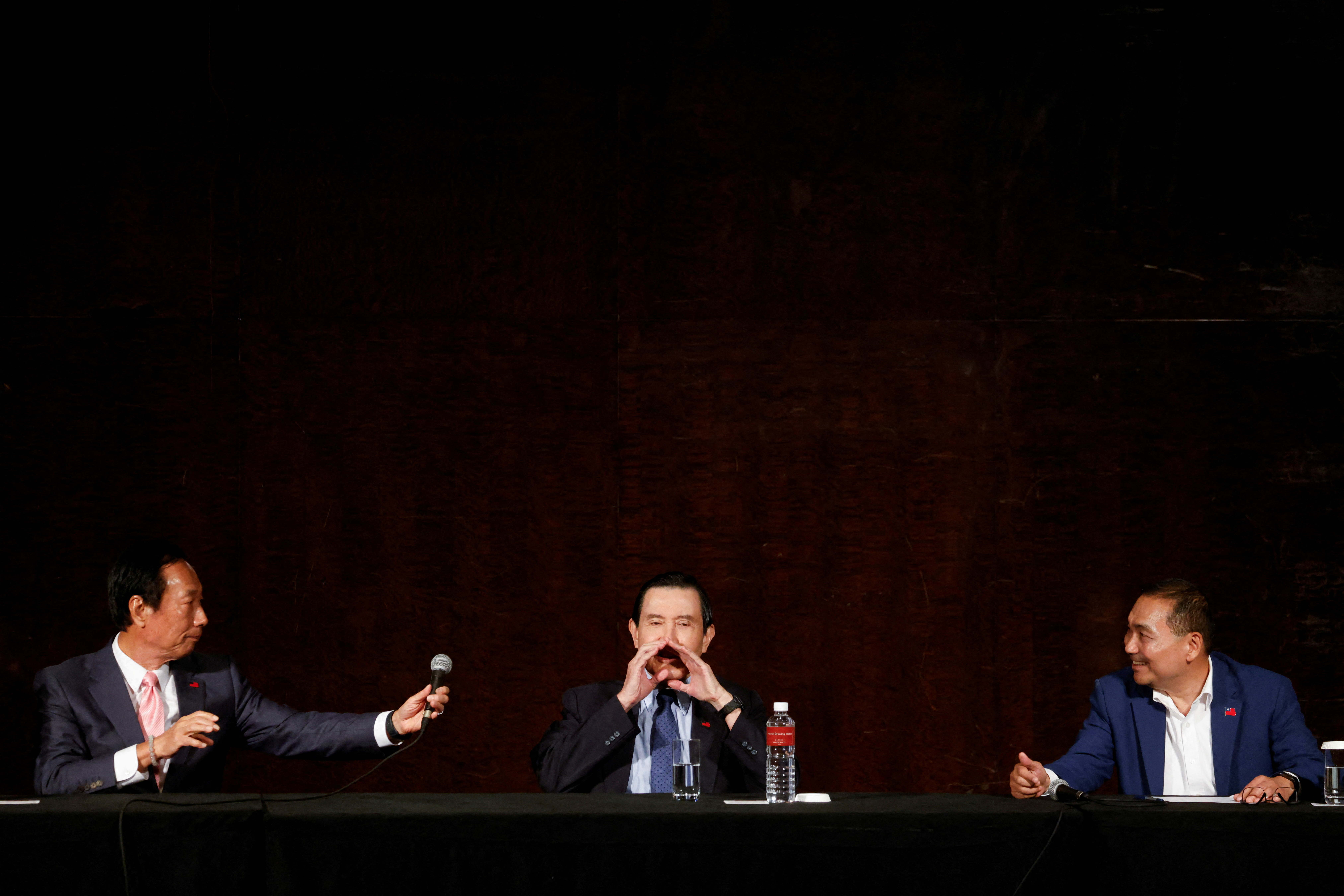 Foxconn founder Terry Gou, former President and KMT stalwart Ma Ying-jeou, and KMT presidential candidate Hou Yu-ih. They are seated at a table againt a black backdrop. They all seem to be talking at once.