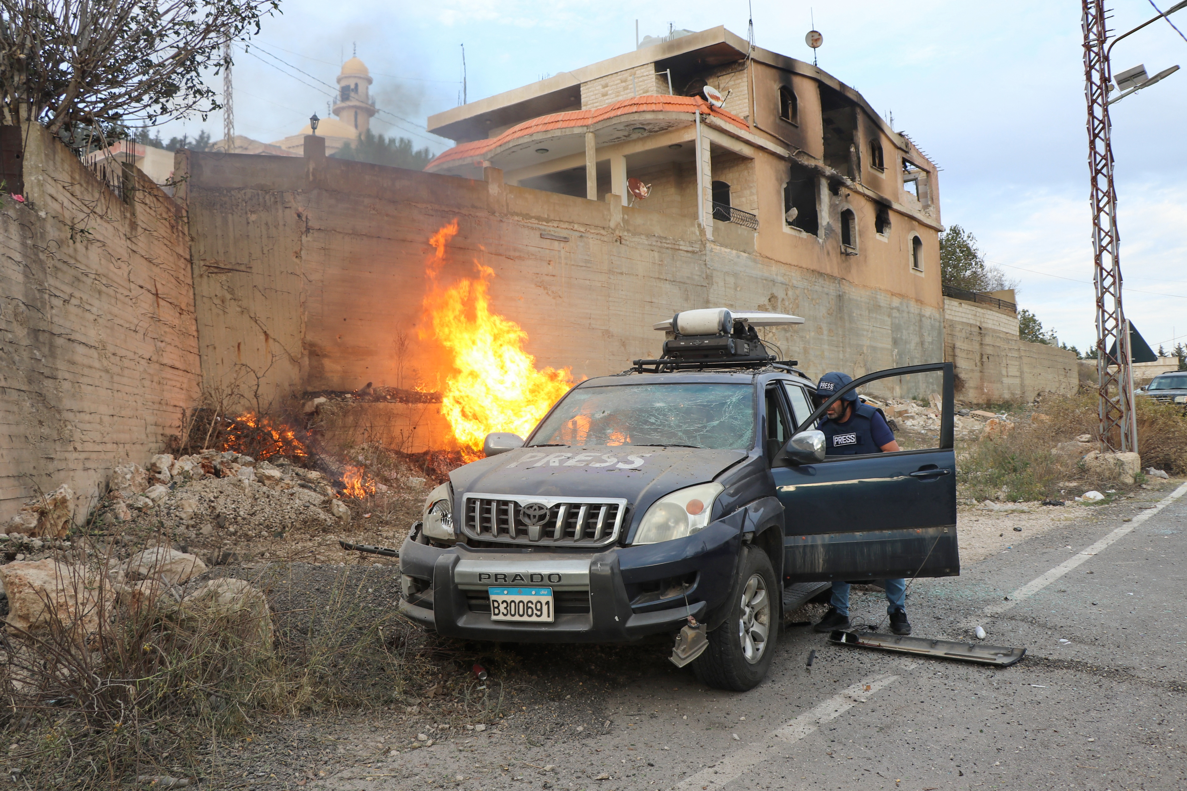 Flames erupt next to a press car
