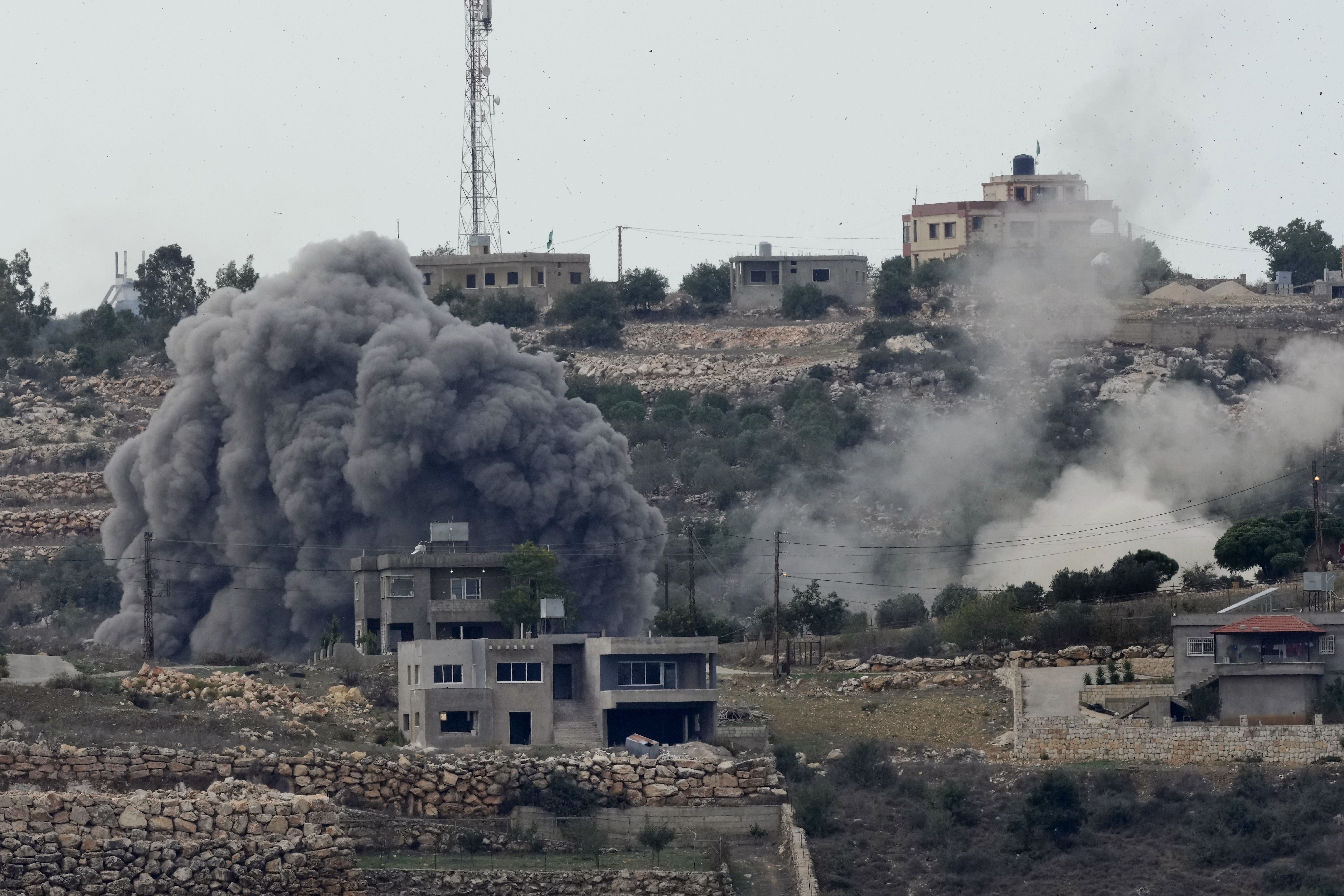 Smoke rises from an Israeli air strike, left, and artillery shelling, right, on the outskirts of Aita al-Shaab, a Lebanese border village with Israel in south Lebanon, November 13, 2023