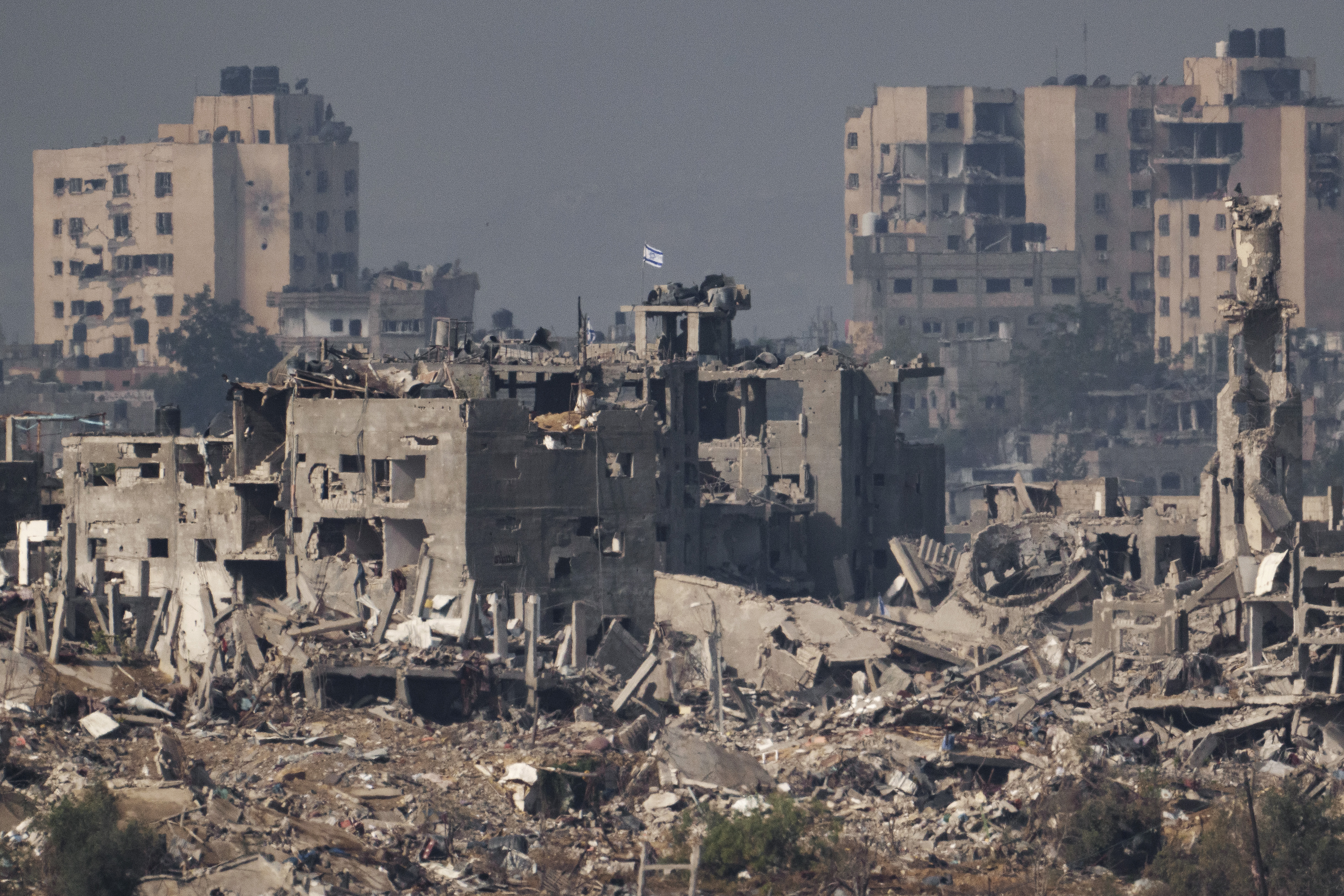 An Israeli flag stands on the top of a destroyed building in the Gaza Strip, as seen from southern Israel, Wednesday, Nov. 15, 2023. [AP Photo/Leo Correa]