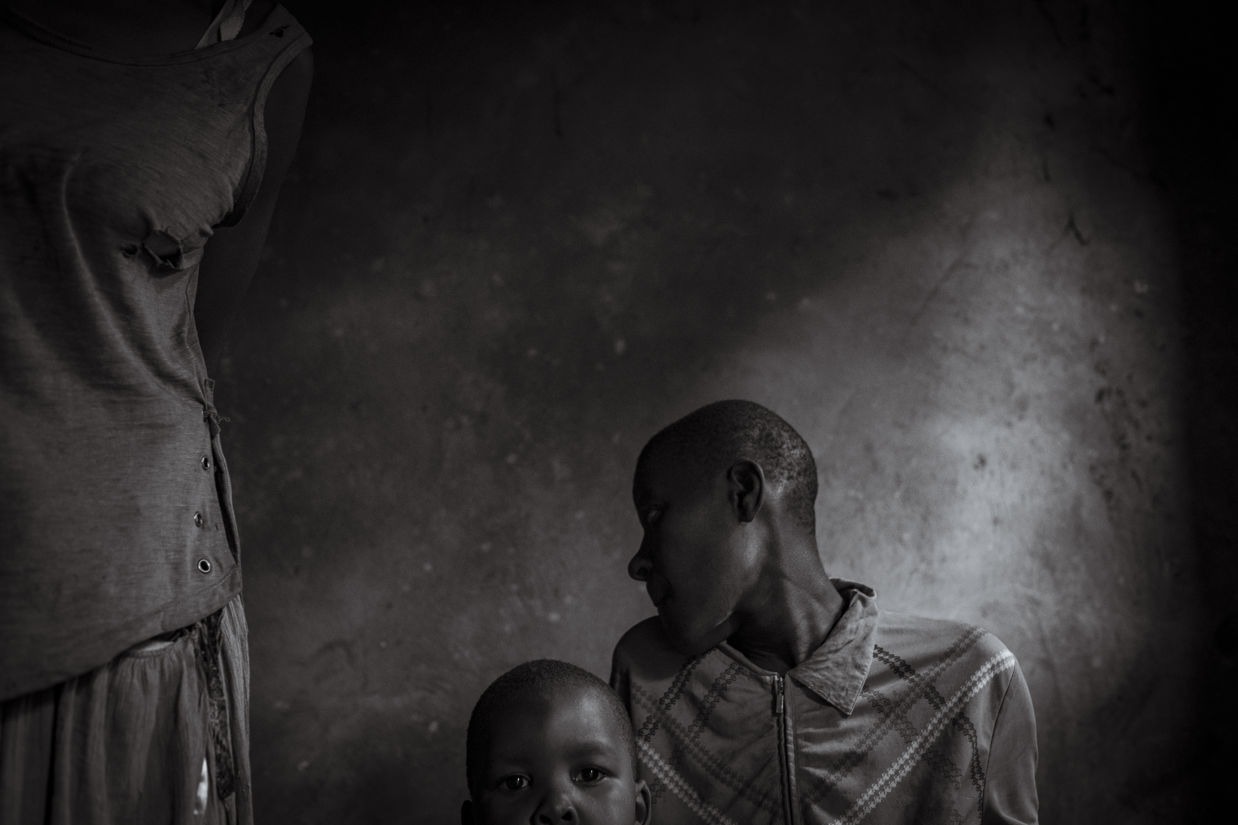 A victim of rape, 20-year-old Katherine Muwunguzi sits with the son she does not know is hers, Edwin, 4, in the room she shares as a sleeping quarter with bags of cassava. Kat lives with an un-diagnosed intellectual disability and is frequently violent towards her mother