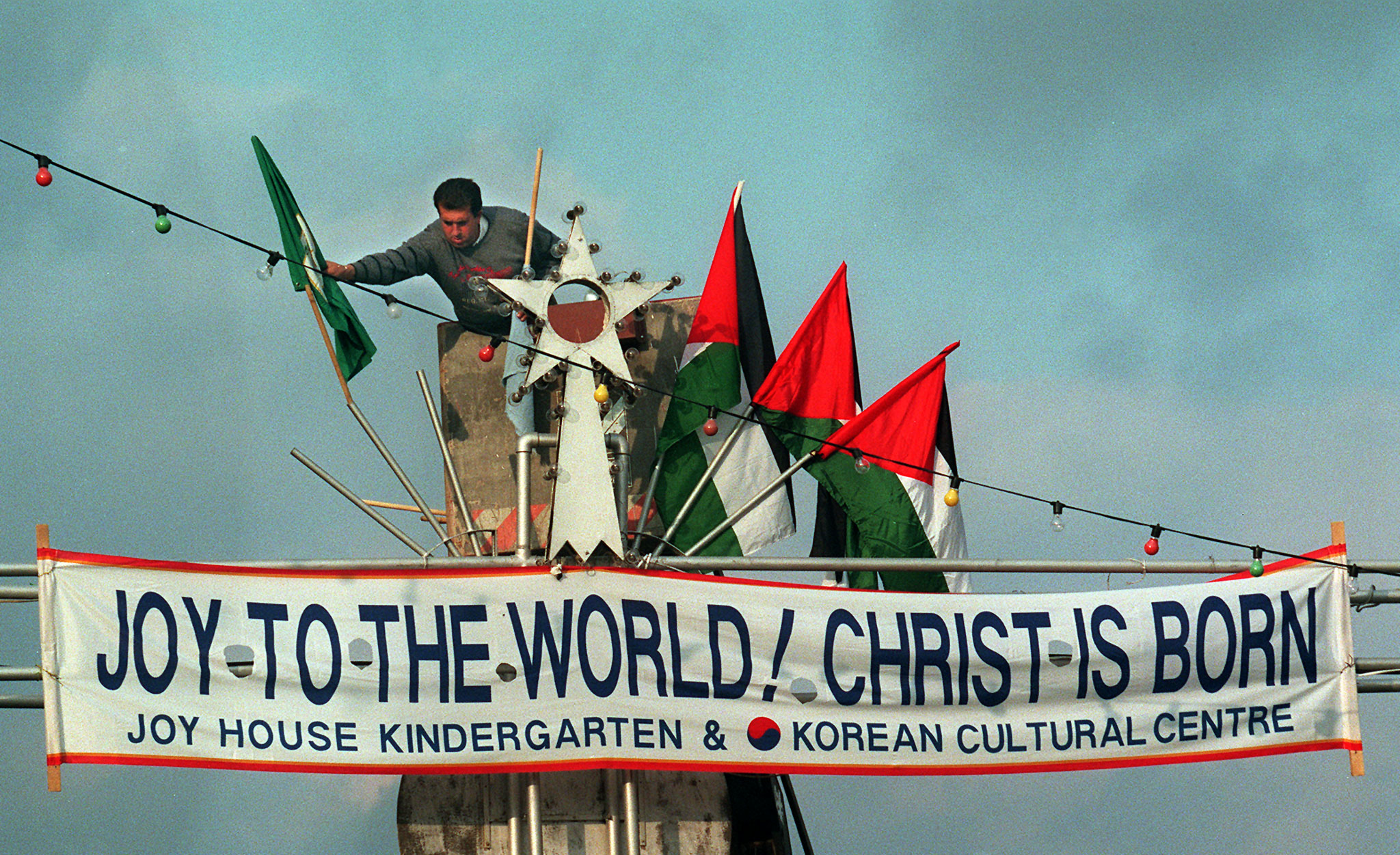 A municipal worker decorates the entrance to Manger Square with Palestinian and City of Bethlehem flags, near the Church of the Nativity, the traditional birthplace of Jesus Christ December 23. Foreign tourists for the most part have shied away from this biblical town, put off by security concerns.