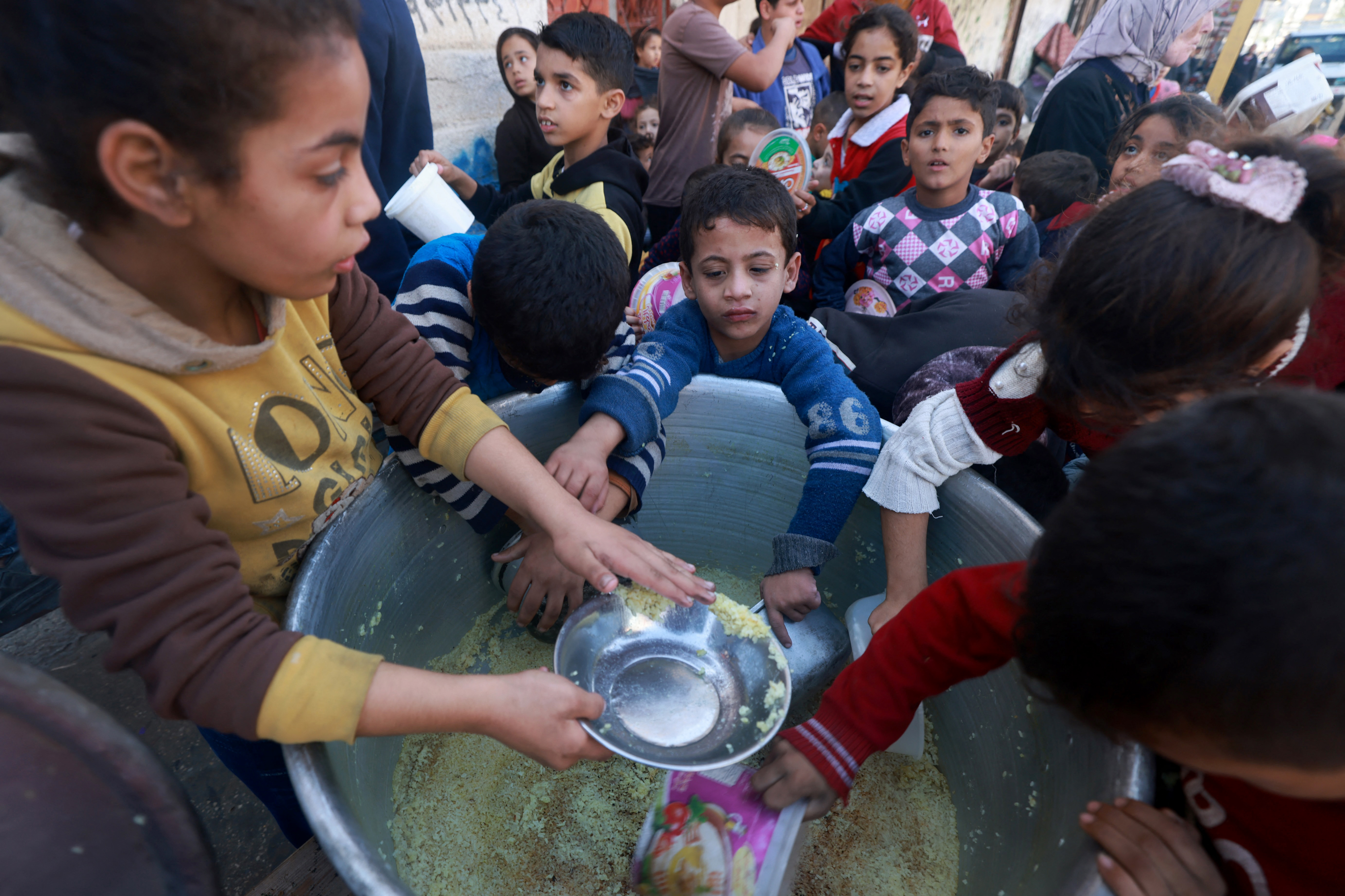 Palestinian children collect food at a donation point provided by a charity group in the southern Gaza Strip city of Rafah, on December 6, 2023