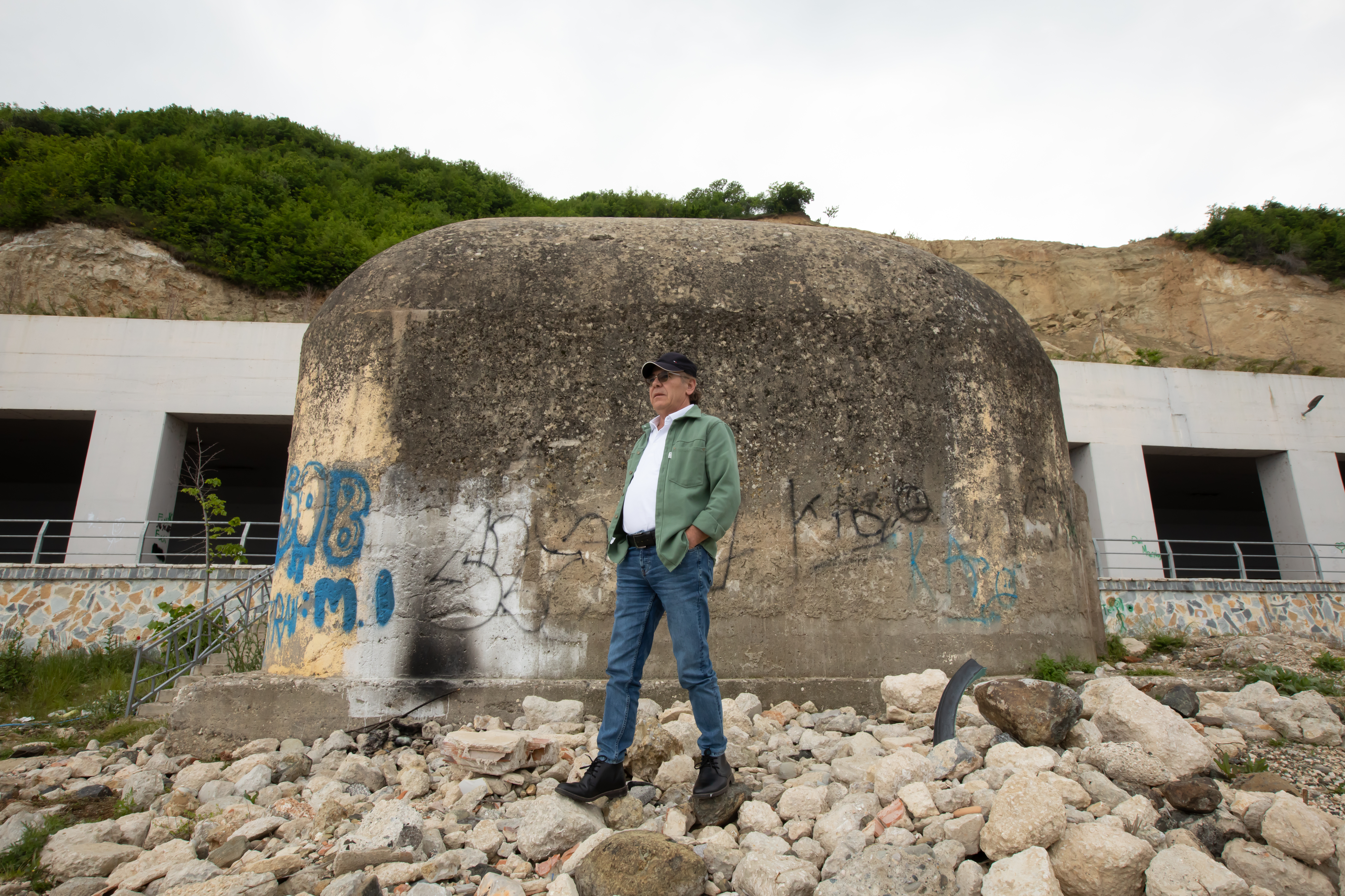 Bajram stands behind the hill where he guarded the boat before the family’s escape in 1975, behind him is a bunker, which were common under communist rule when invasion by Western countries was feared