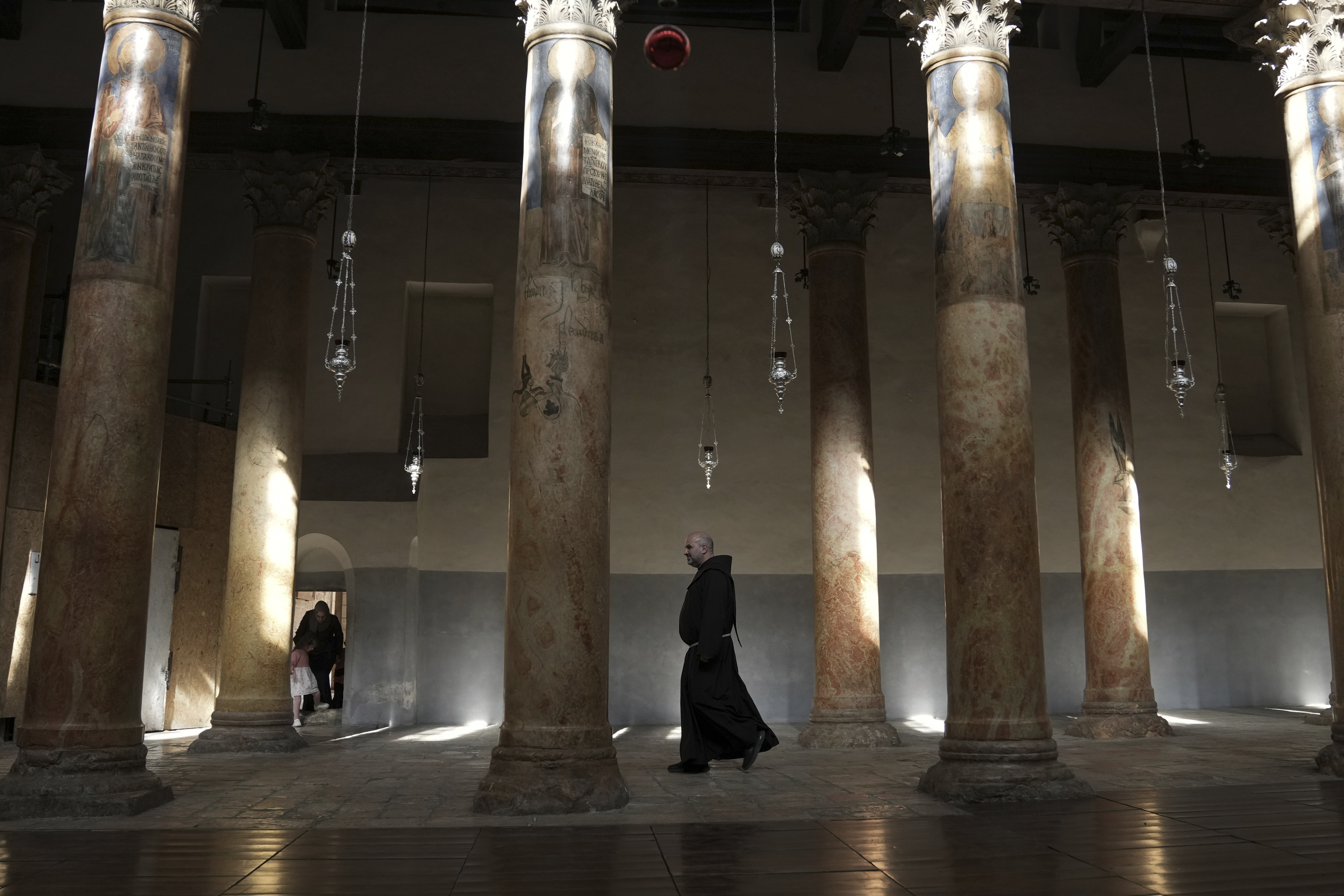 A priest walks at the Church of the Nativity, traditionally believed to be the birthplace of Jesus Christ in the West Bank town of Bethlehem, Saturday, Dec. 16