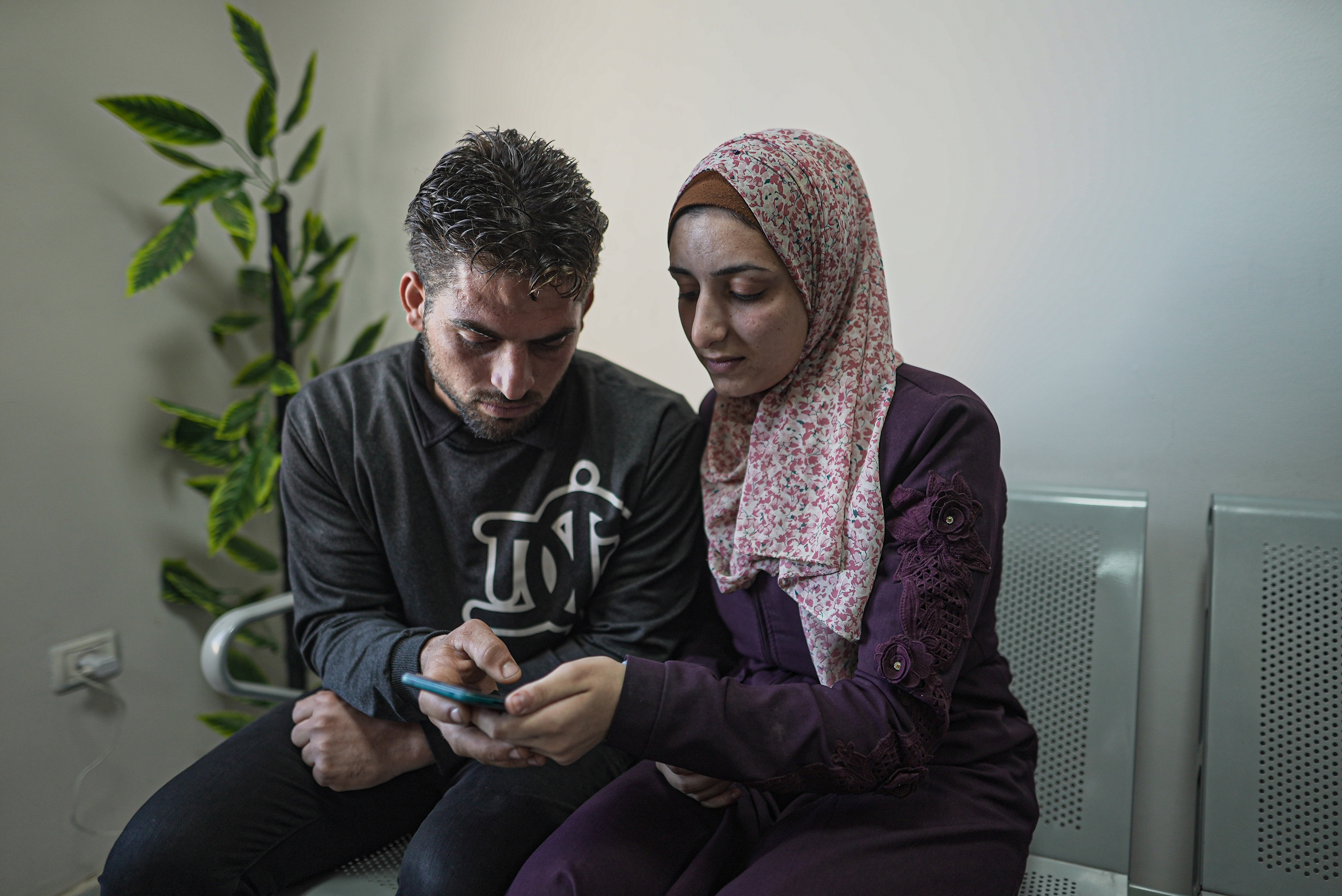 Noor and her husband, Huthaifa, look at photos of their baby boy on her phone. They have not seen him for weeks